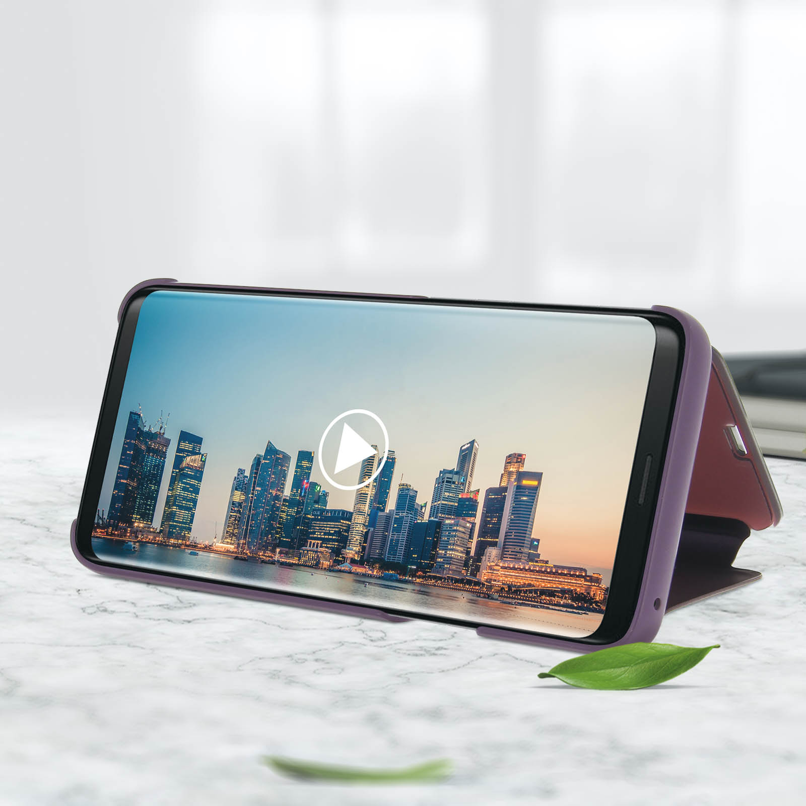 Smartphone en una funda morada, mostrando un video de paisaje urbano, sobre superficie de mármol.