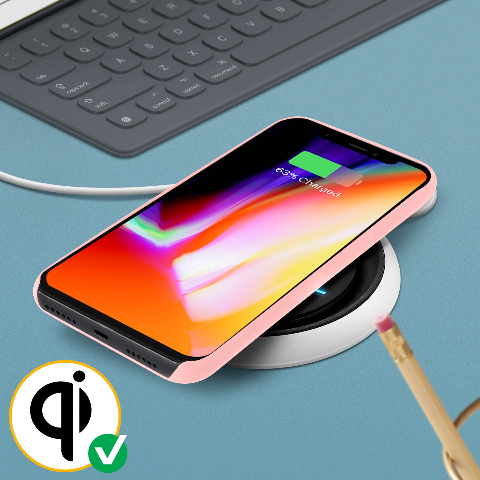 Telefoon op een draadloze oplader. Roze telefoonhoesje, potlood en toetsenbord op de tafel.