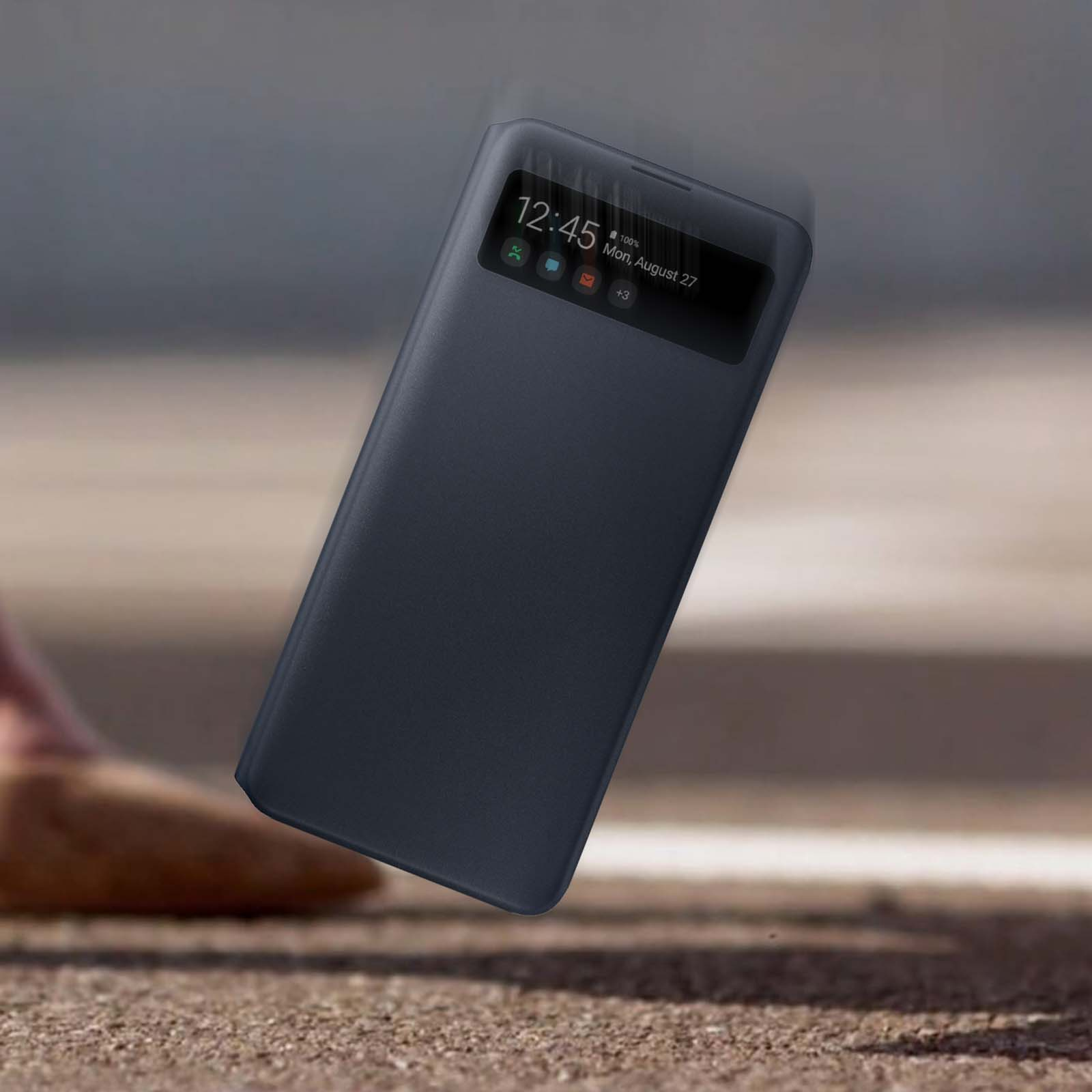 Custodia per telefono blu scuro in caduta. Lo schermo mostra ora, data e icone. Lo sfondo è sfocato.