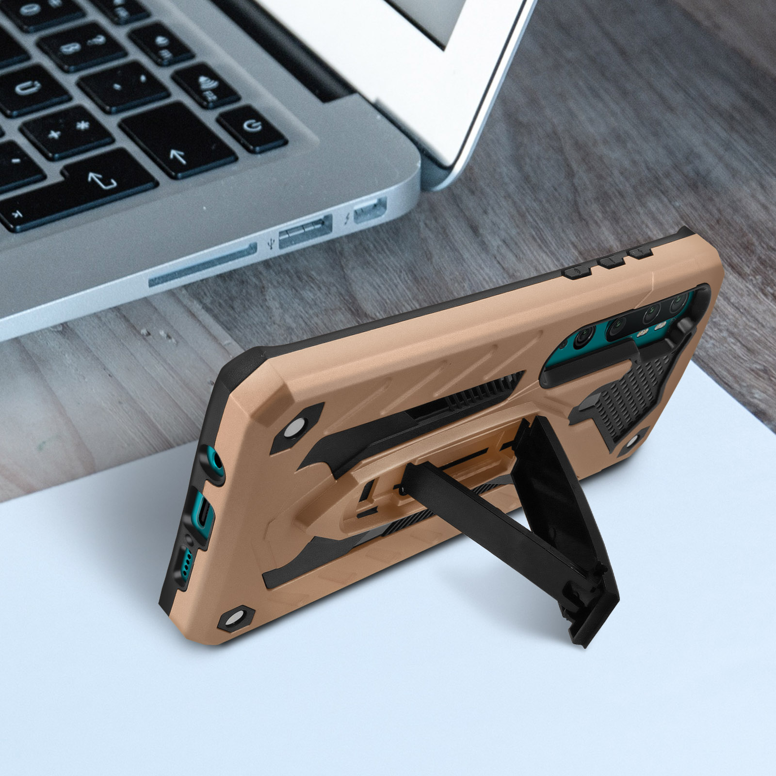 Una custodia per telefono con un supporto, appoggiata su una scrivania con un laptop. La custodia è beige.
