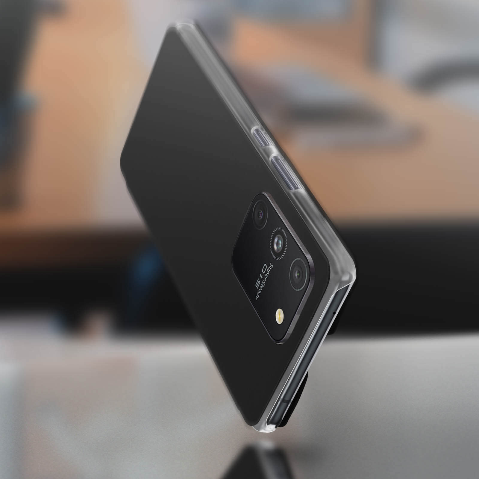 Custodia nera con retro trasparente, angolata, che mostra la fotocamera del telefono e uno sfondo sfocato.