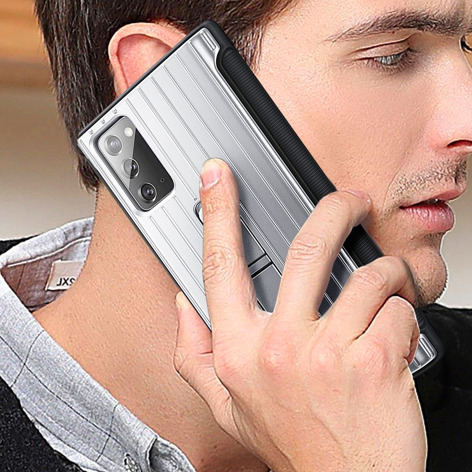 Ein Mann hält eine silberne Telefonhülle an sein Ohr. Die Hülle hat ein gestreiftes Design und einen erhöhten Kamerabereich.