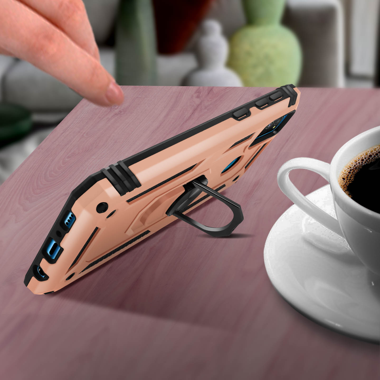 Custodia per telefono con cavalletto, posta su un tavolo con tazza di caffè, la custodia è dorata.