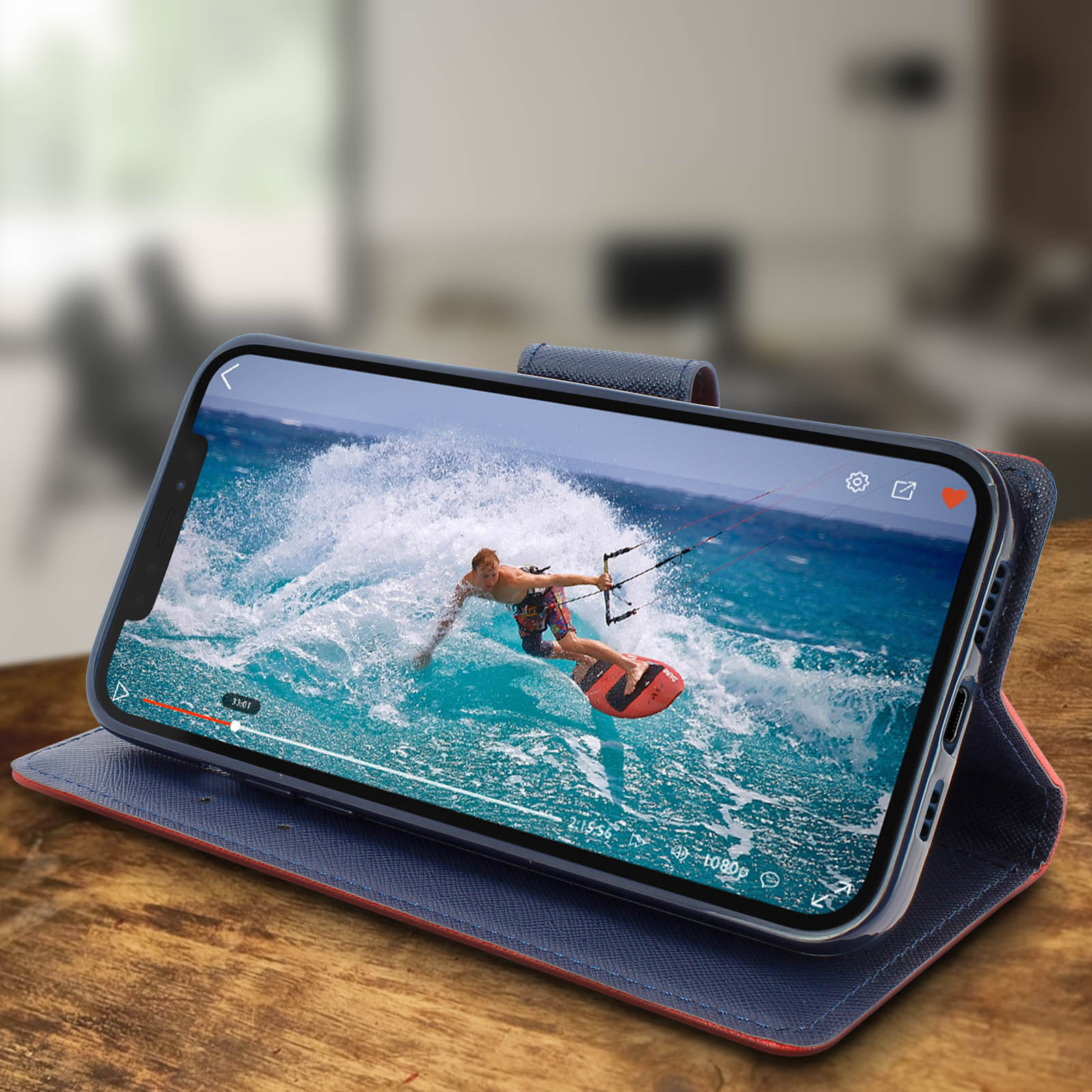 Custodia per telefono con video di un kitesurfer. Telefono in custodia blu e arancione su tavolo di legno.