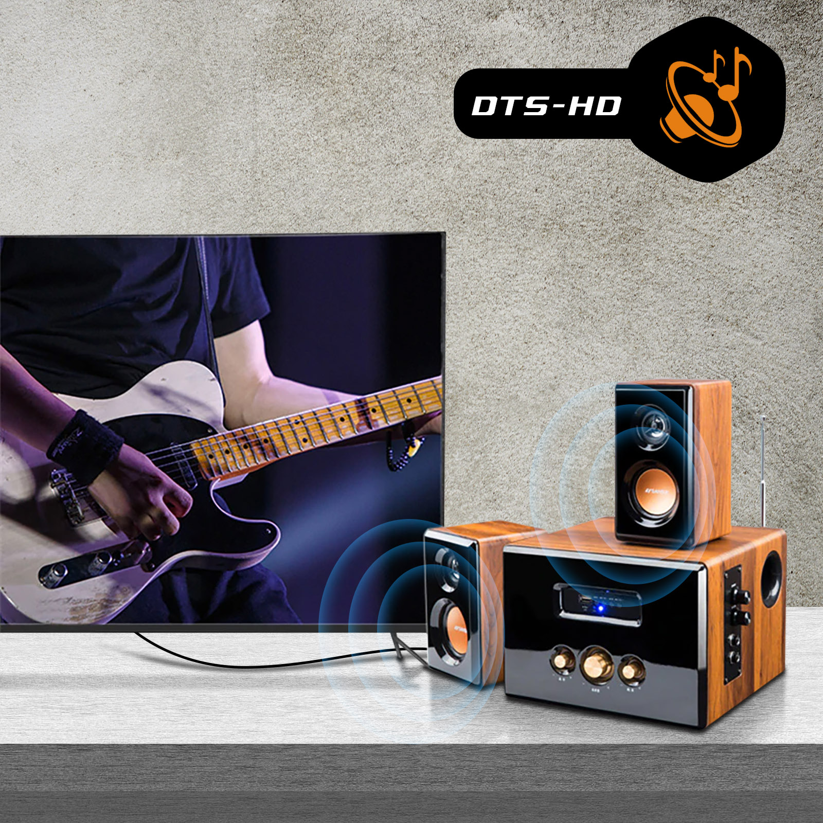 Una TV e altoparlanti configurati. Una persona suona la chitarra con un plettro.