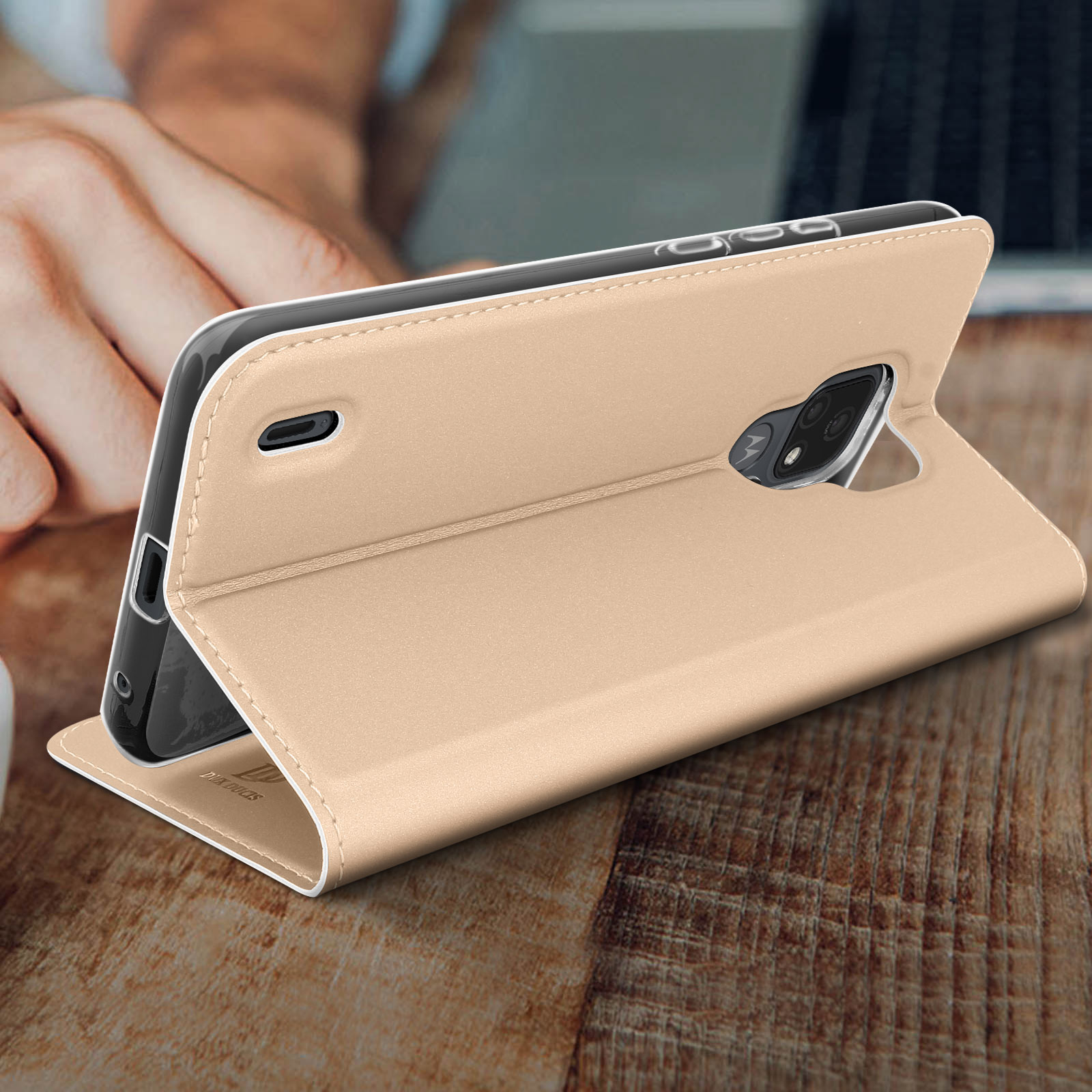 Una custodia dorata per telefono, aperta e che tiene un telefono su una superficie di legno.