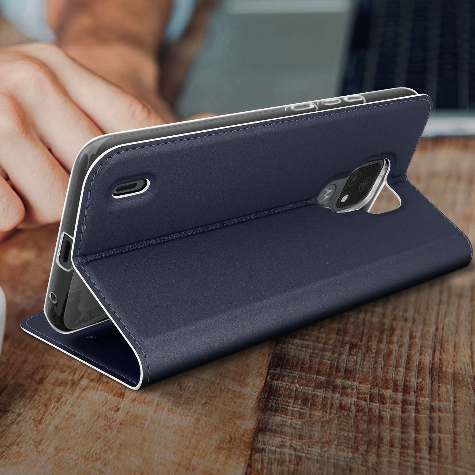 Una custodia per telefono blu nelle mani di una persona, aperta sul tavolo di legno.
