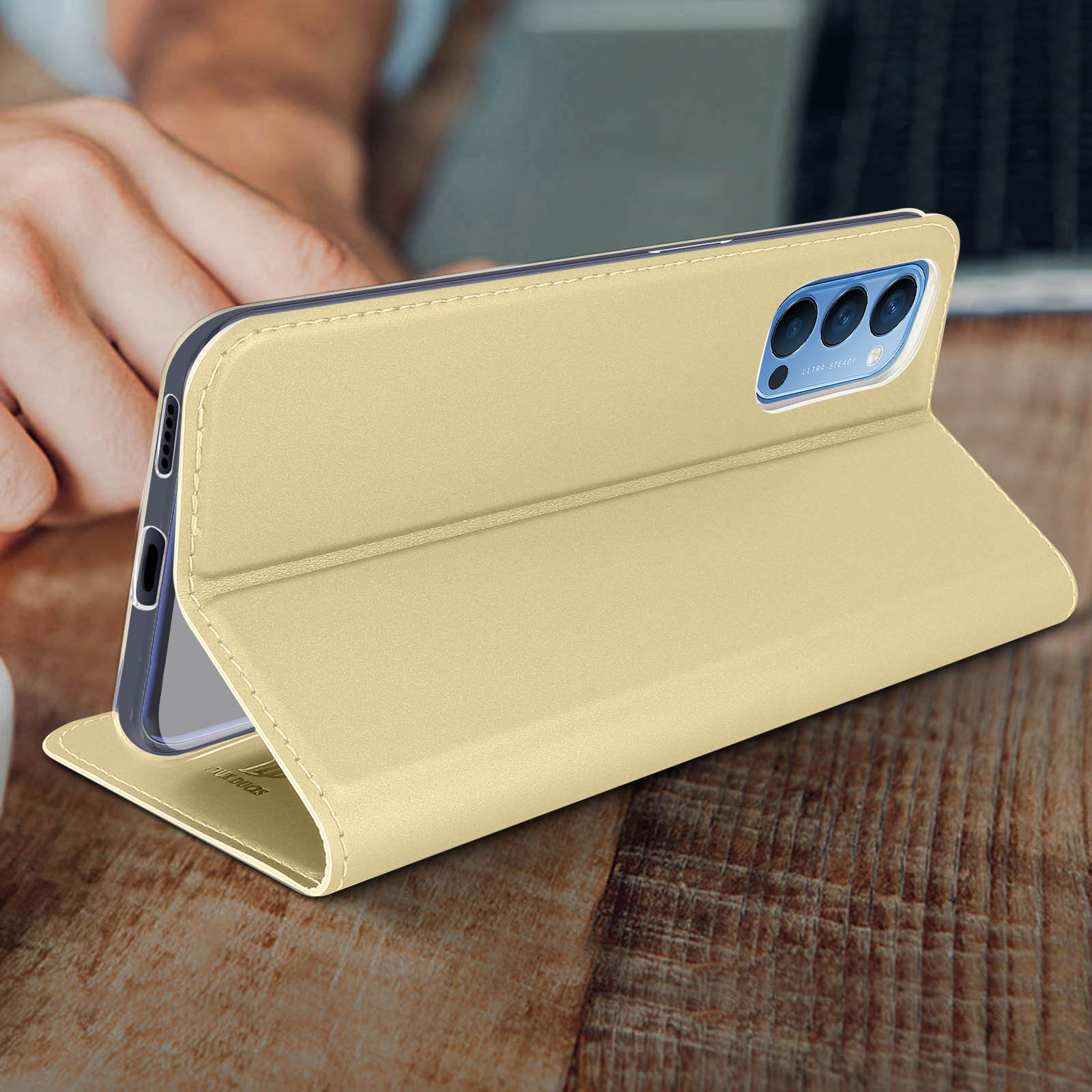 Ein Telefon in einer goldenen Hülle ist auf einem Holztisch aufgeklappt. Die Hülle ist abgewinkelt.