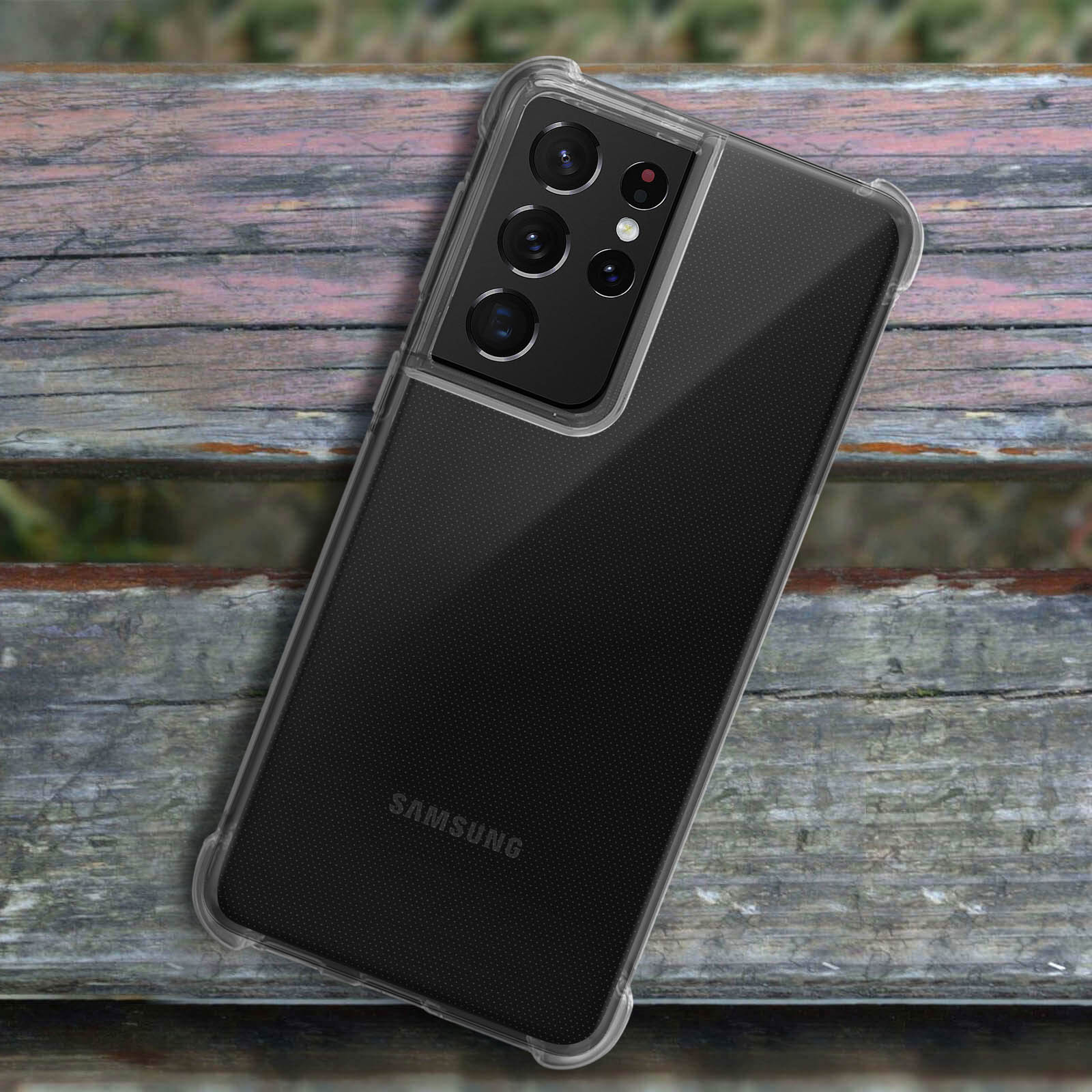 Un telefono in una custodia trasparente. Il telefono è appoggiato su una superficie di legno. Il telefono ha più fotocamere.