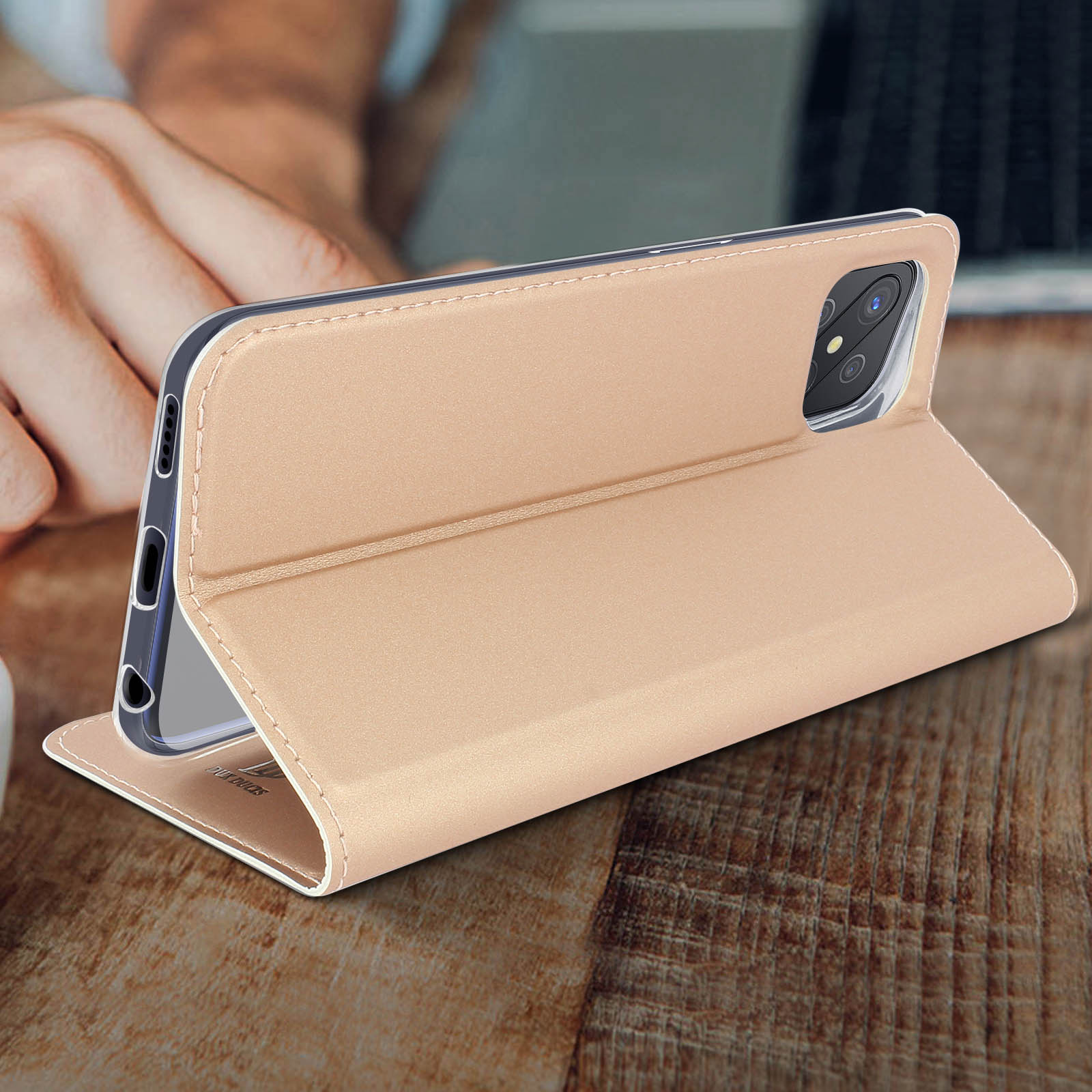 Un telefono in una custodia marrone chiaro è aperto su un tavolo di legno. La custodia è angolata.