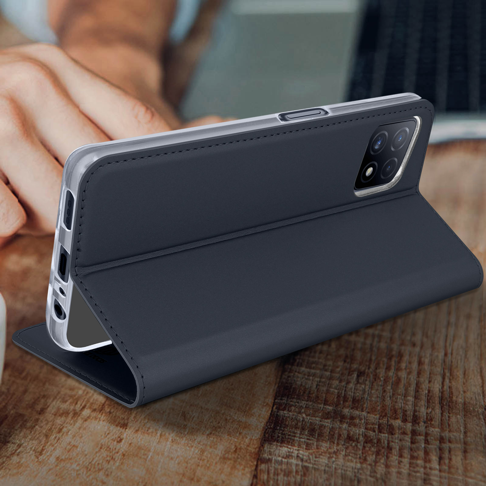 Un telefono in una custodia, aperto. È su una superficie di legno. La custodia è blu scuro, schermo visibile.