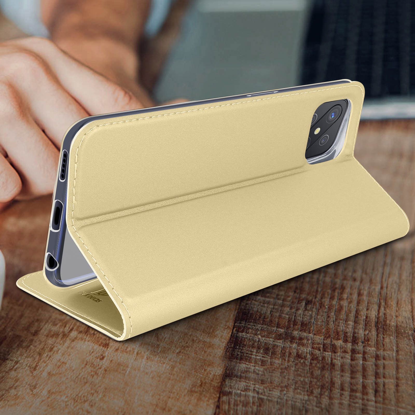 Un telefono in una custodia beige è aperto. La custodia è su una superficie di legno.