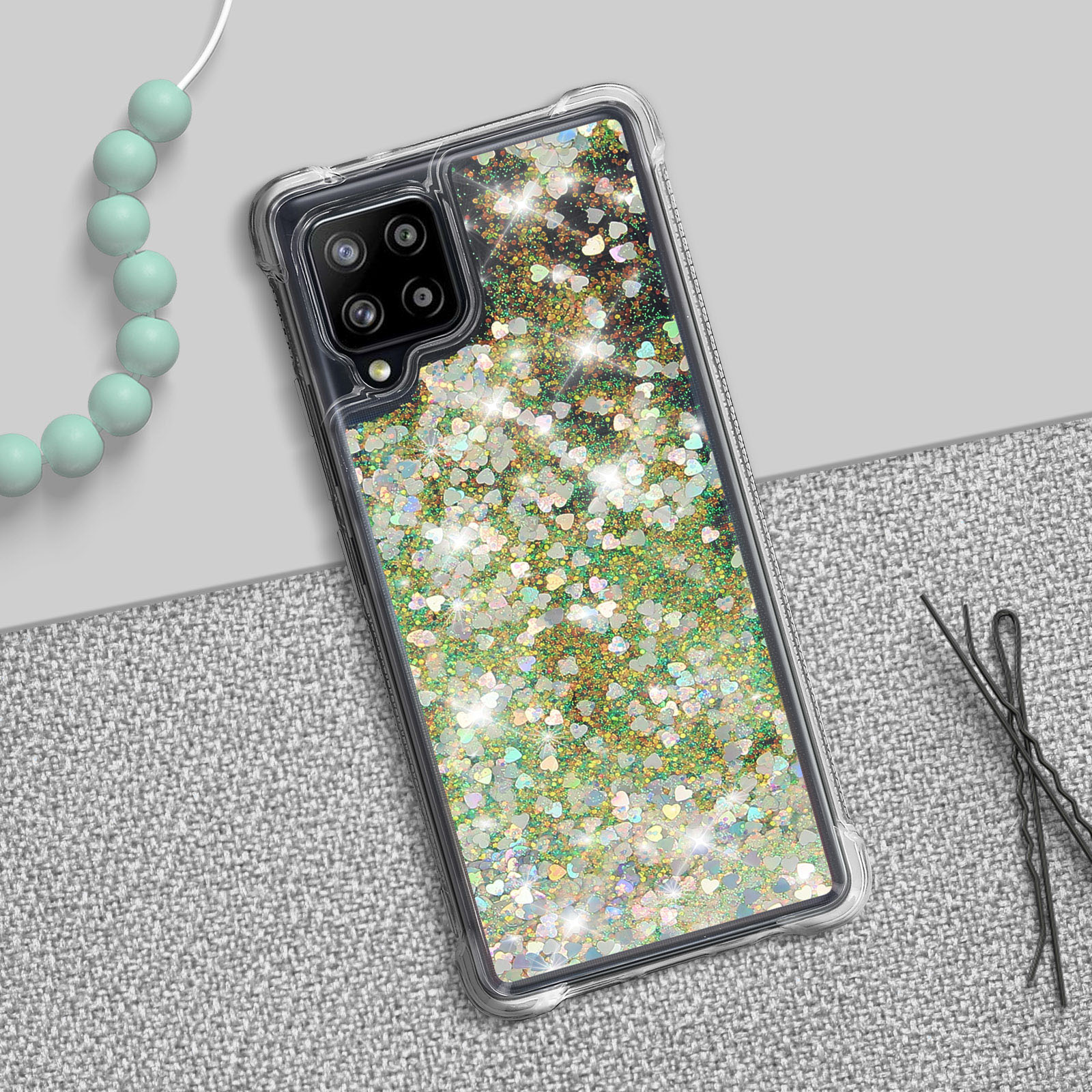 Custodia trasparente per telefono con cuori glitterati. Perline e forcine per capelli sul tavolo.