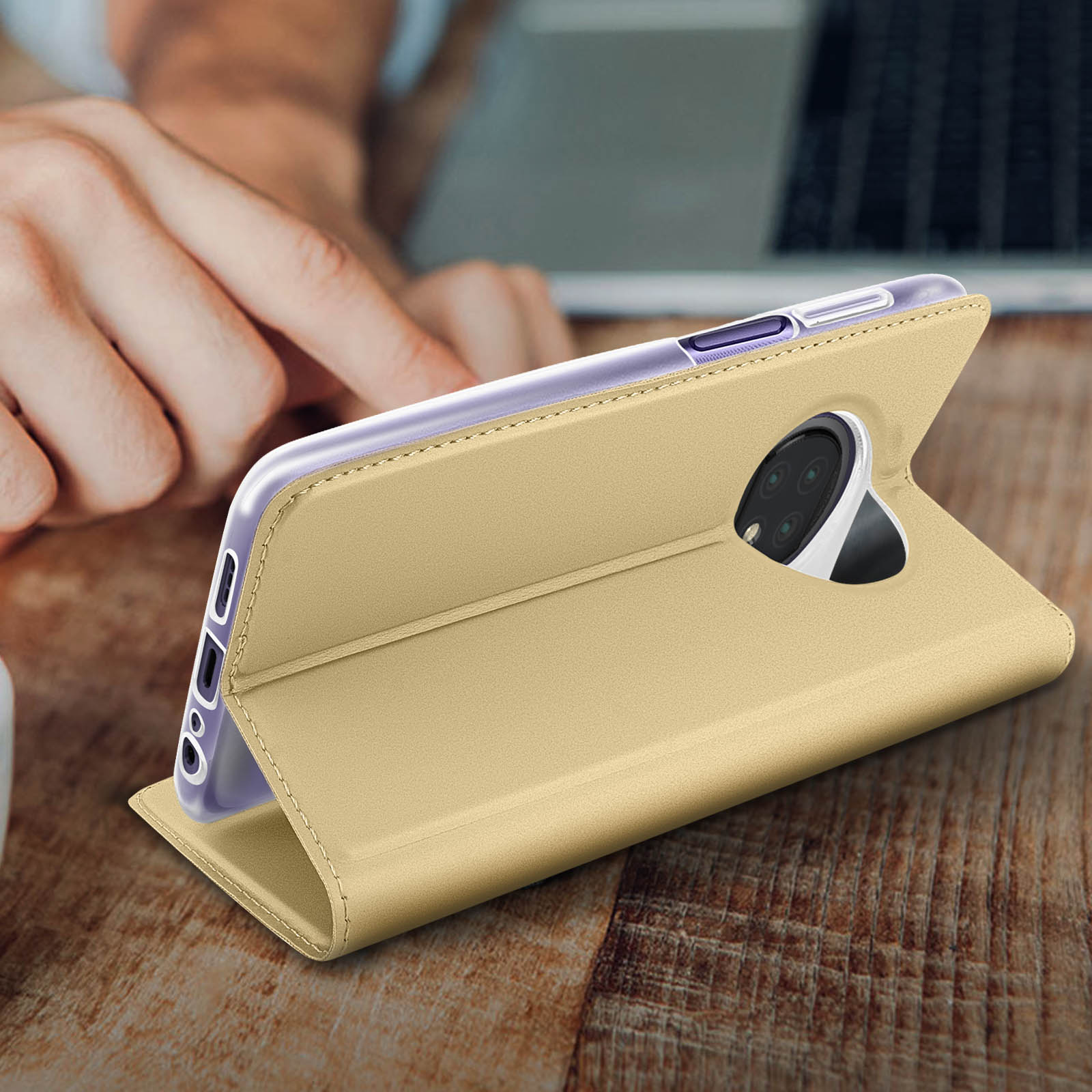 Telefon in goldener Hülle auf Holztisch, Hand im Blick.