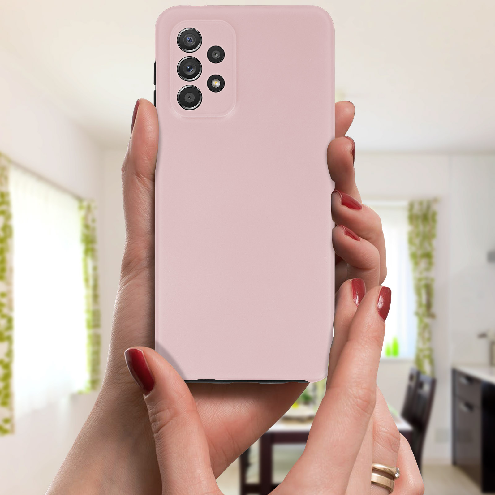 Une coque de téléphone rose tenue par des mains avec du vernis à ongles rouge dans un environnement flou.