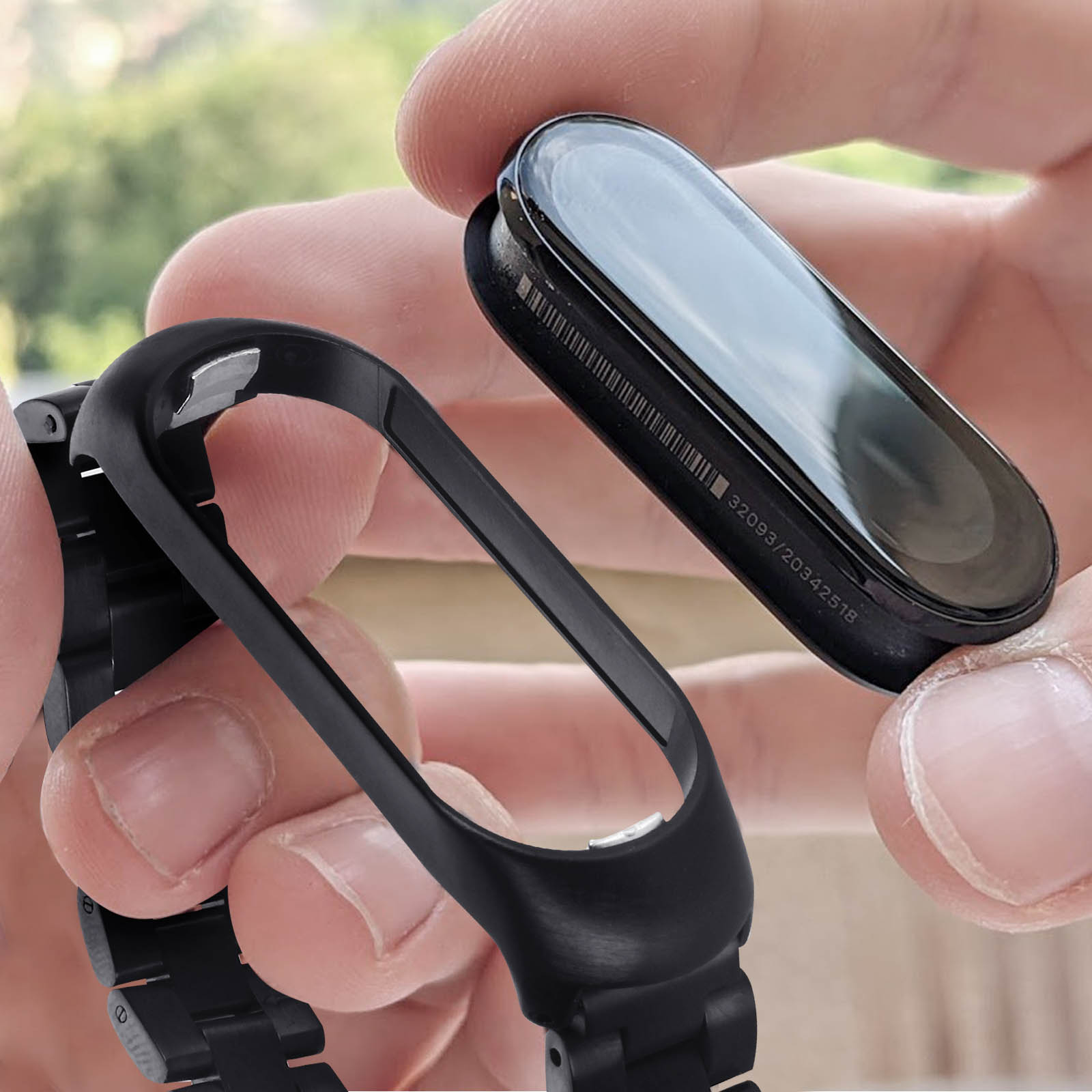 Una persona che tiene un braccialetto Mi Band con schermo e cinturino staccati.