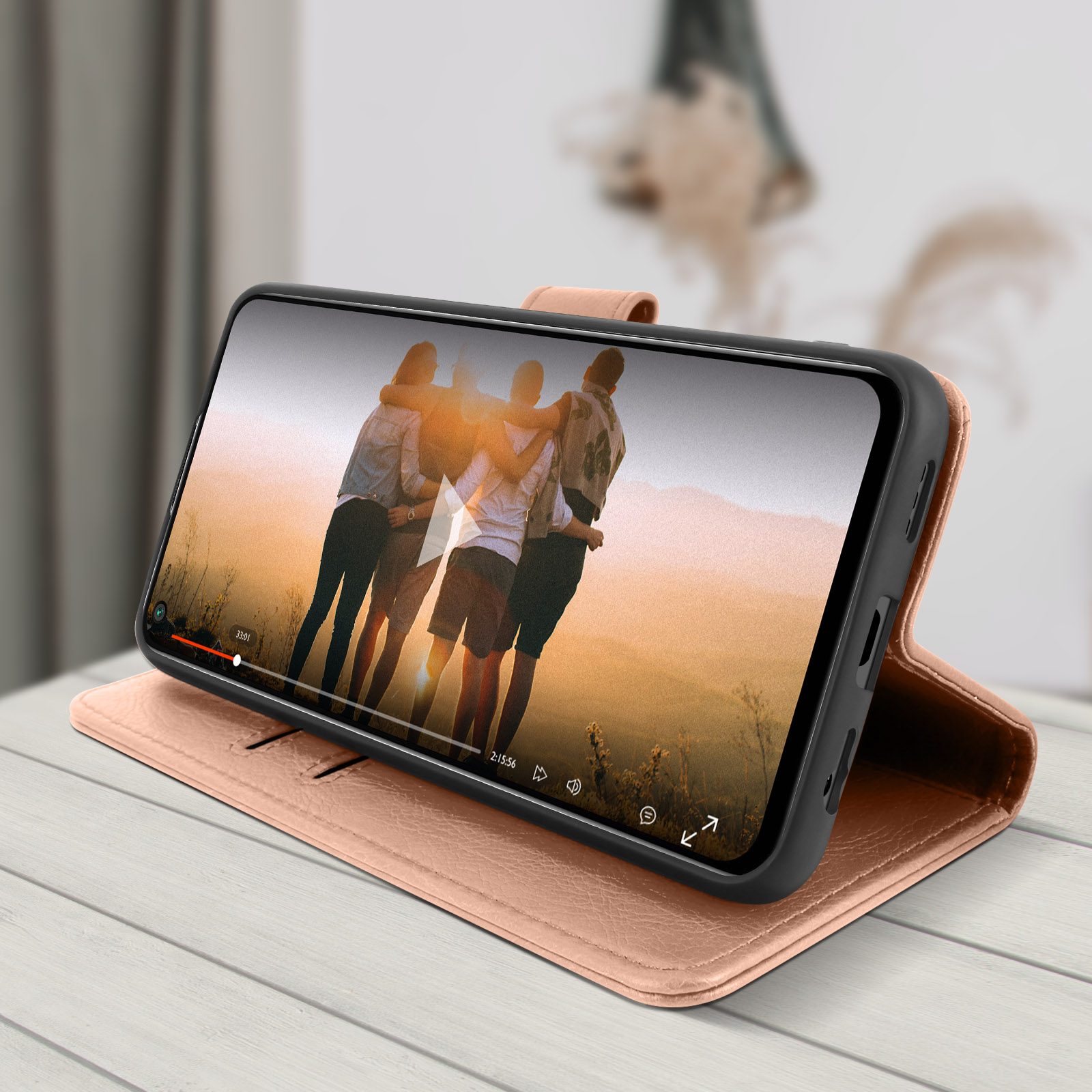 Ein Telefon in einem rosa Gehäuse, das ein Video von sich umarmenden Personen zeigt. Das Gehäuse befindet sich auf Holz.