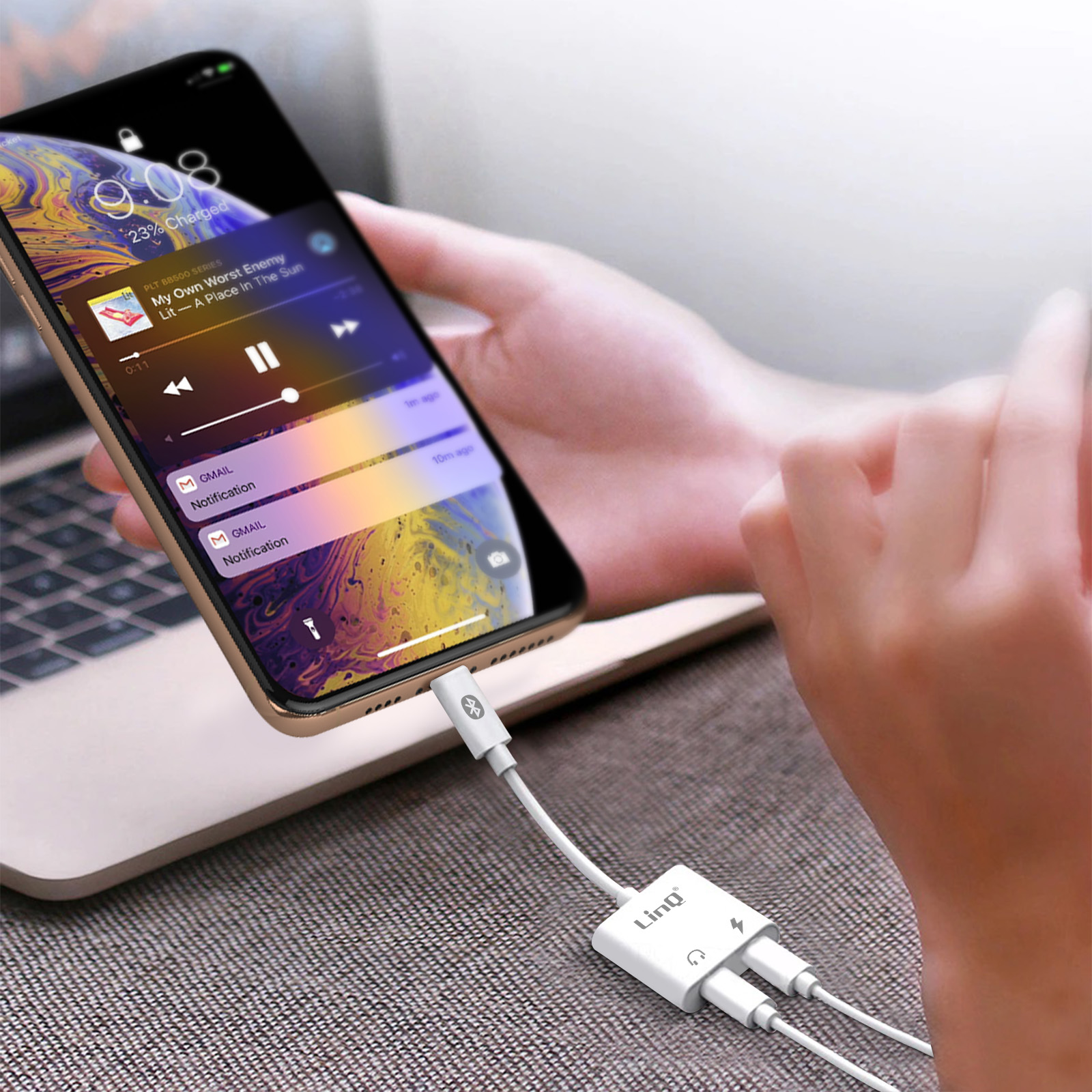 Eine Person hält ein Telefon mit einem Anschluss an einen Audio-Splitter. Das Telefon zeigt Musiksteuerungen.