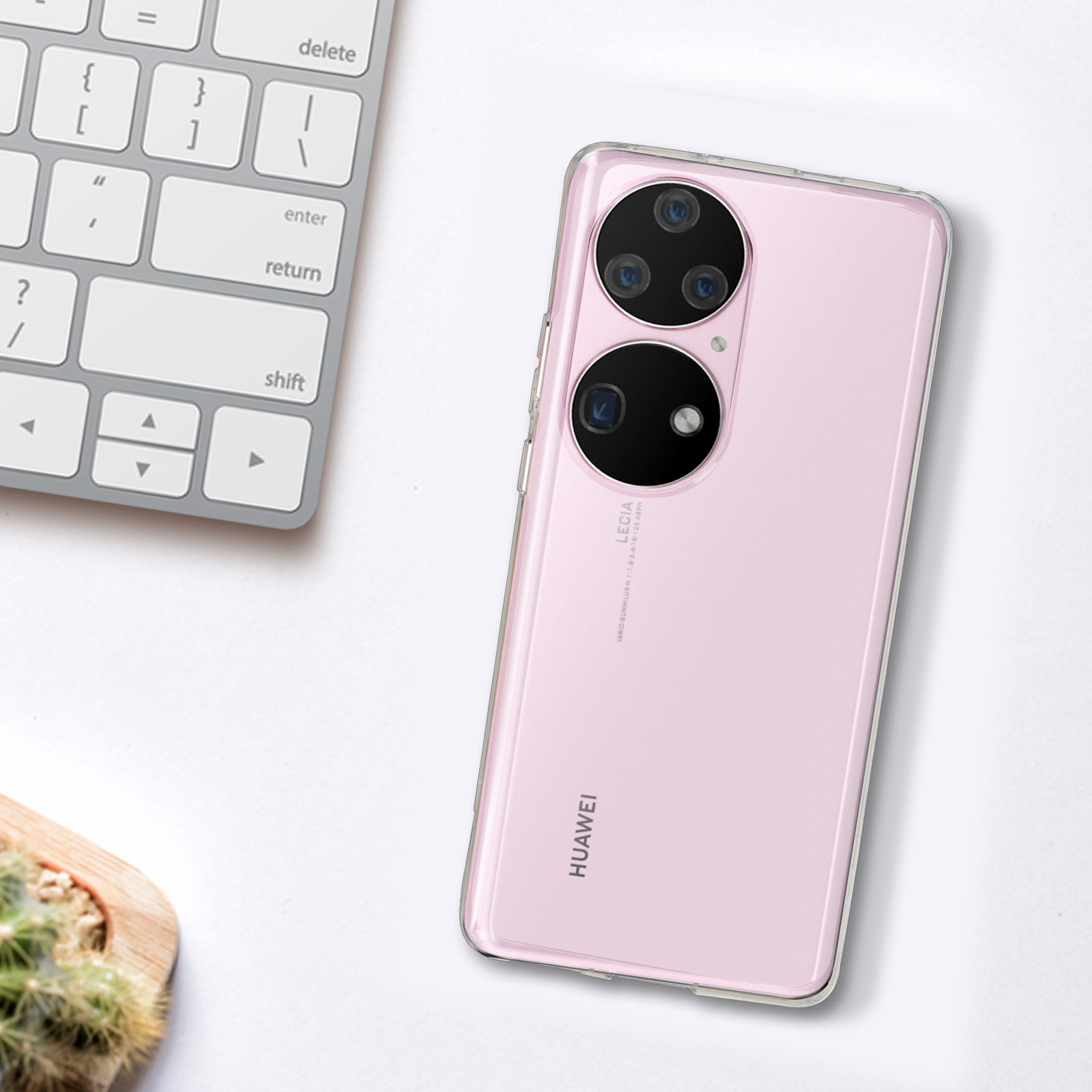 Ein pinkfarbenes Telefon in einer transparenten Hülle, auf einem Schreibtisch mit Tastatur.