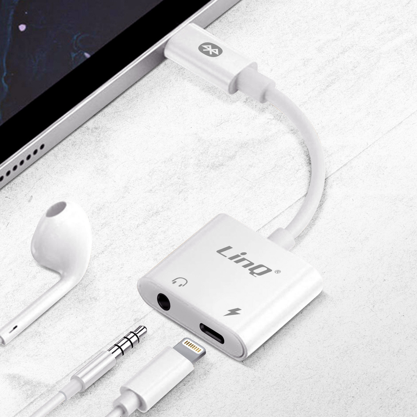 Adaptateur audio blanc avec connecteurs Lightning et aux, à côté d'un écouteur blanc.