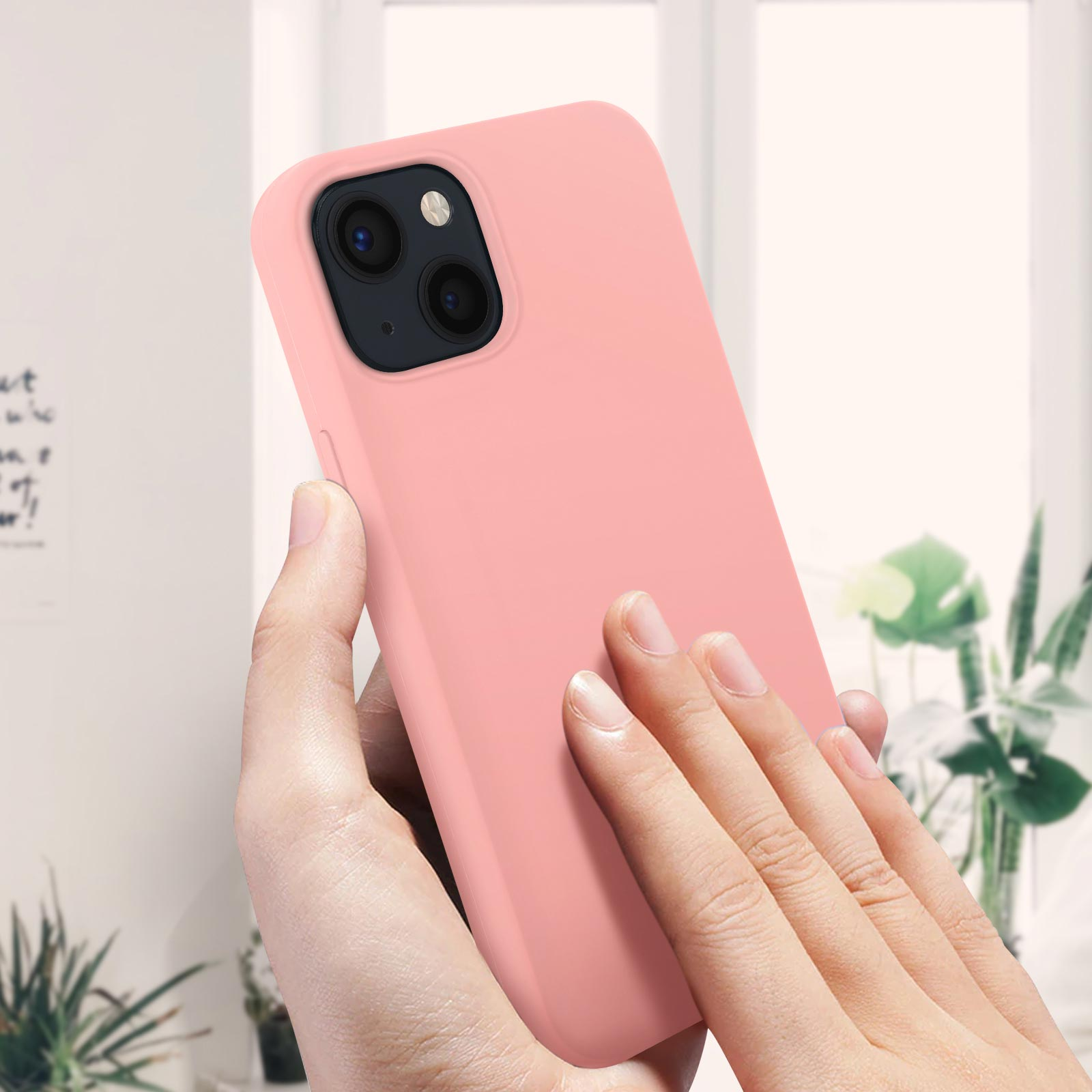 Una mano tiene in mano una custodia per telefono rosa chiaro. La custodia ha una sporgenza per la fotocamera.