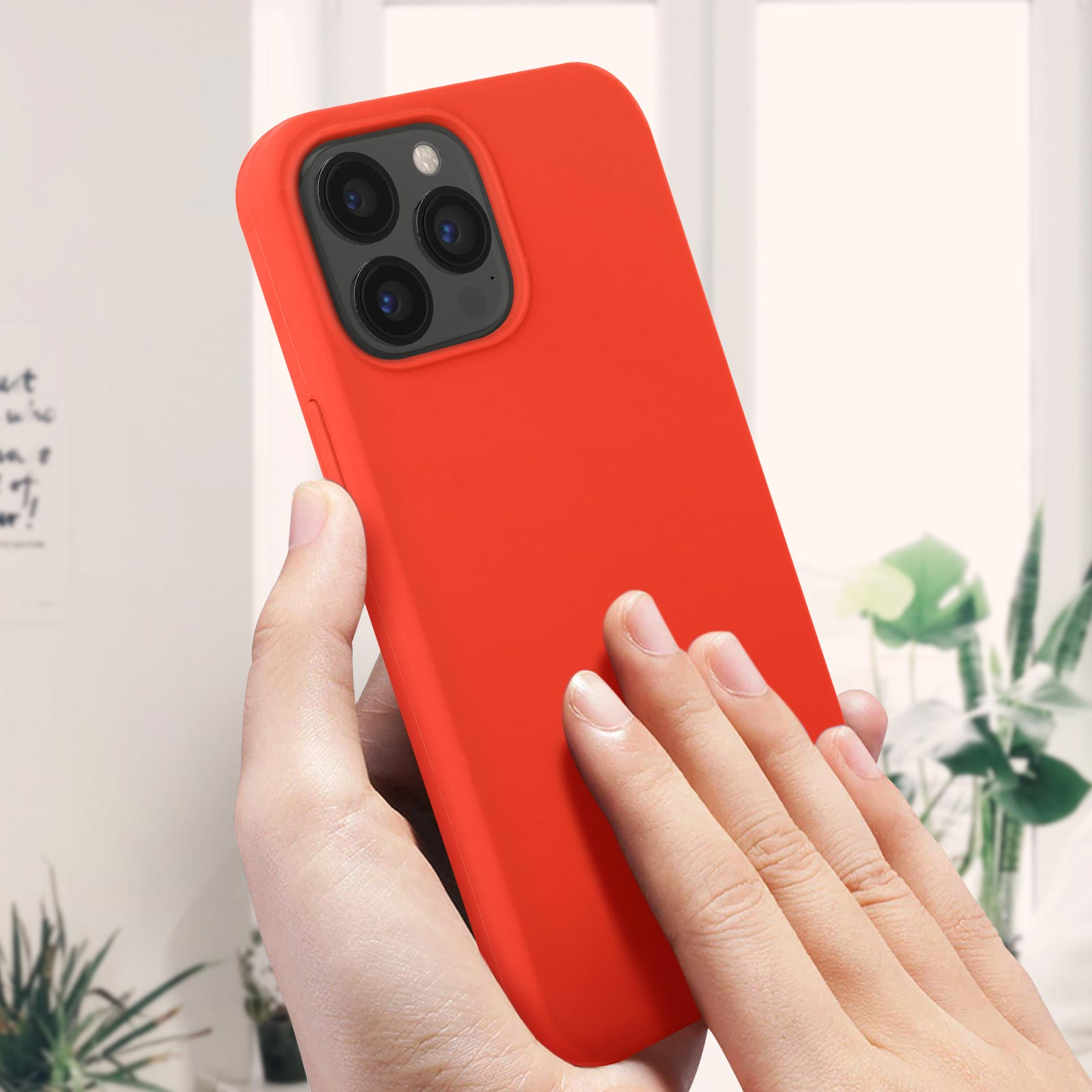 Le mani di una persona che tengono un telefono rosso brillante con tre fotocamere posteriori, inclinato verso l'osservatore.