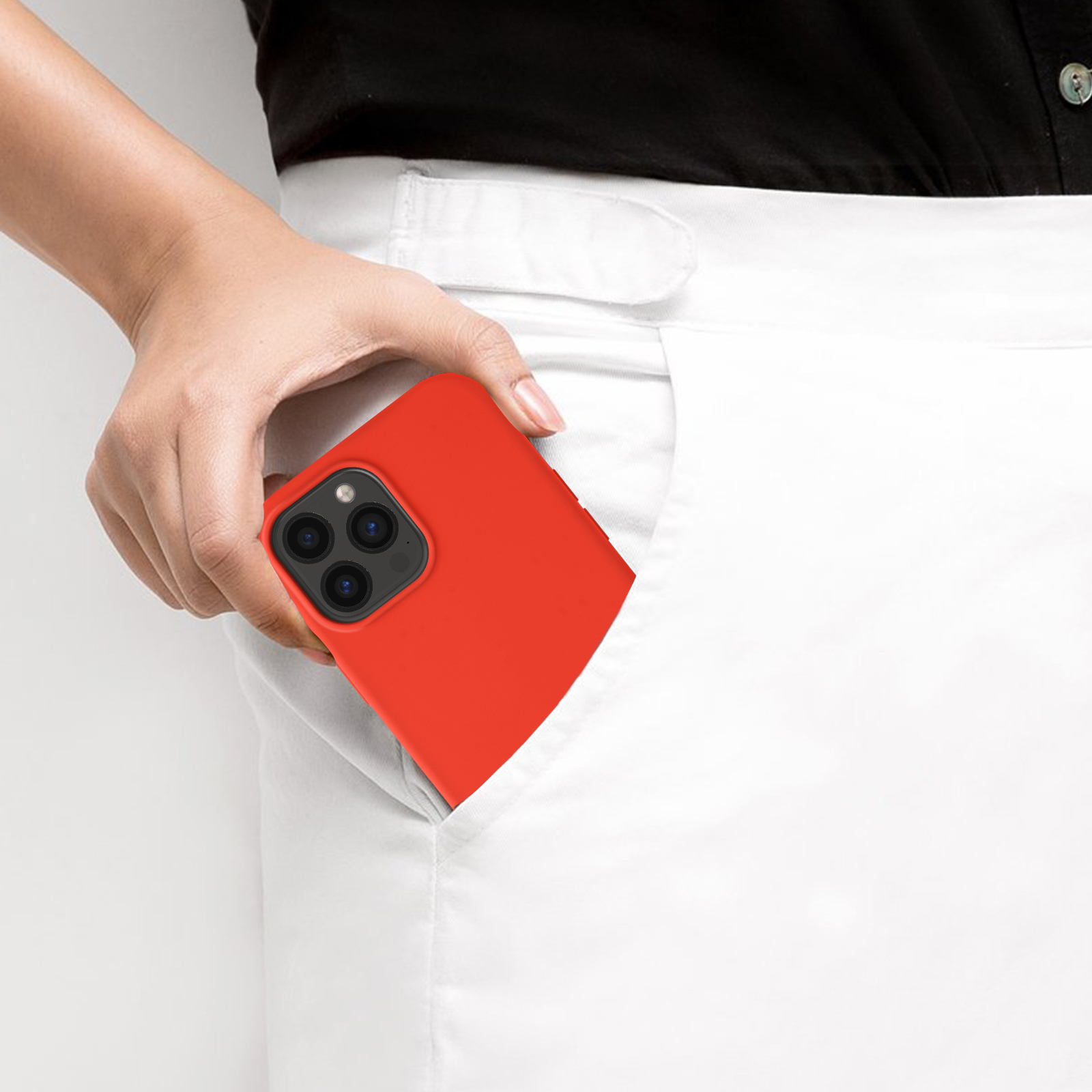 La mano di una persona che tiene un telefono rosso, per lo più in una tasca bianca, con la fotocamera visibile.