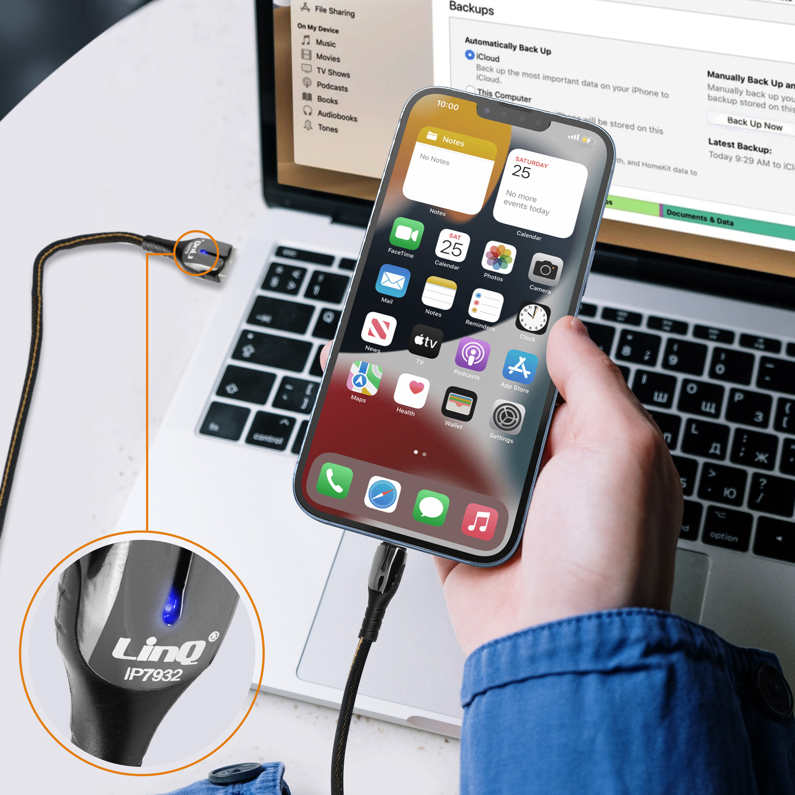 iPhone mit einem Ladekabel an einen Laptop angeschlossen. Hintergrund eines Schreibtisches.