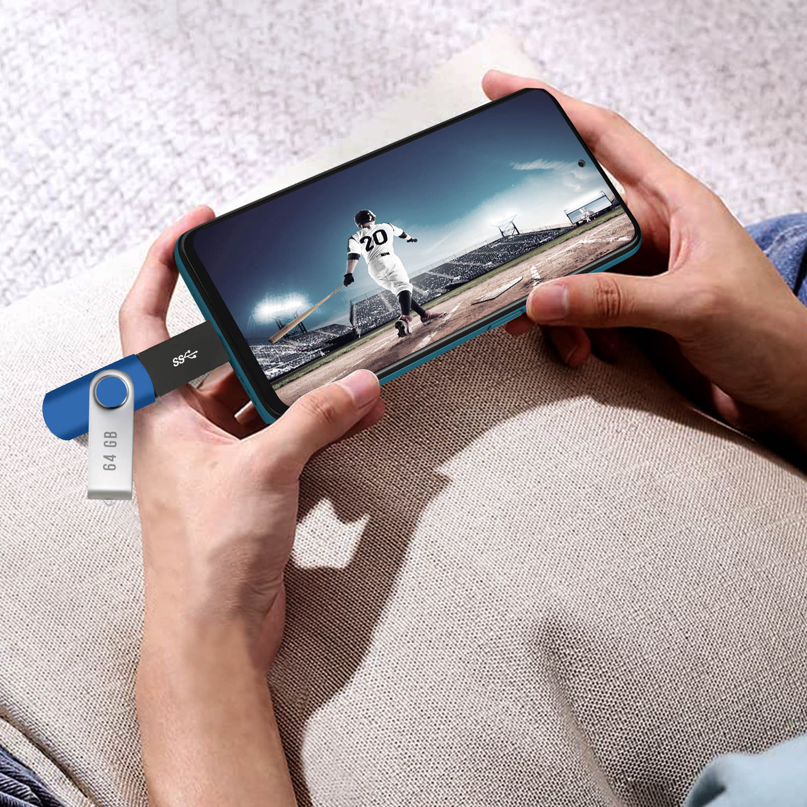 Mani che tengono un telefono con partita di baseball sullo schermo. Penna USB da 64GB collegata.