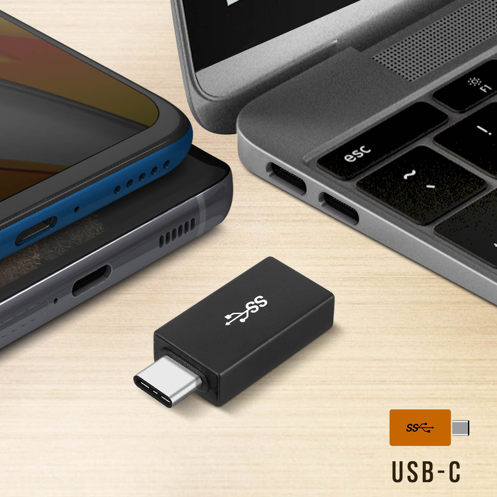 Adattatore USB-C nero accanto a telefono e laptop. Tavolo bianco con logo USB-C. Etichetta USB-C.