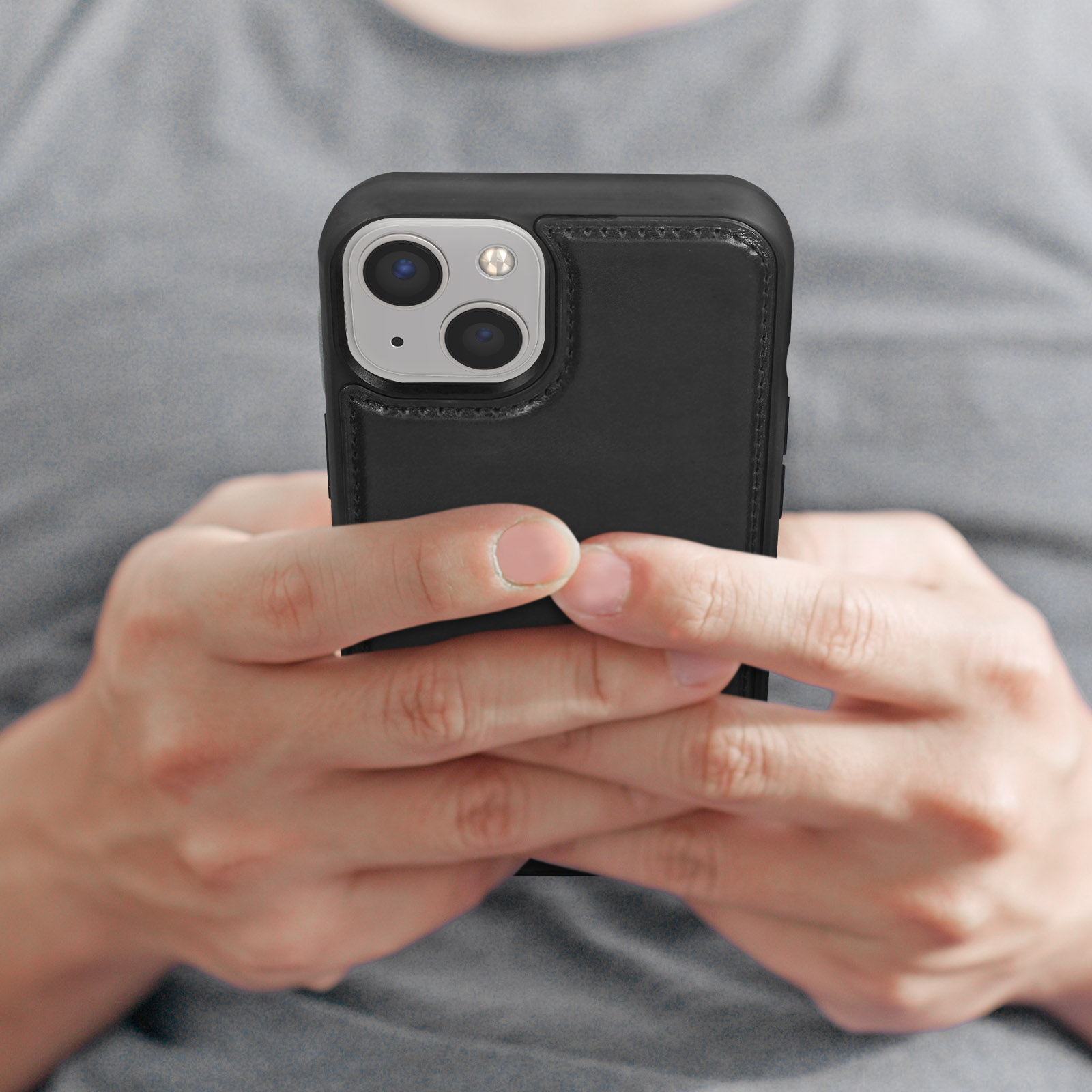 Mani che tengono un telefono con una custodia nera. Il telefono mostra la fotocamera e il flash.