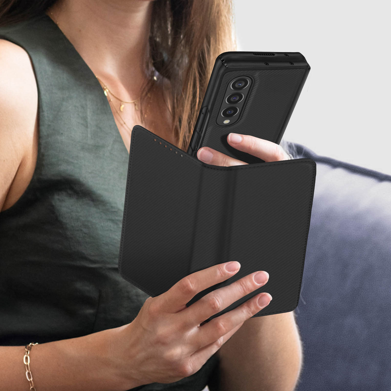 Una donna tiene in mano un telefono pieghevole nero con una custodia scura. Il telefono è aperto.