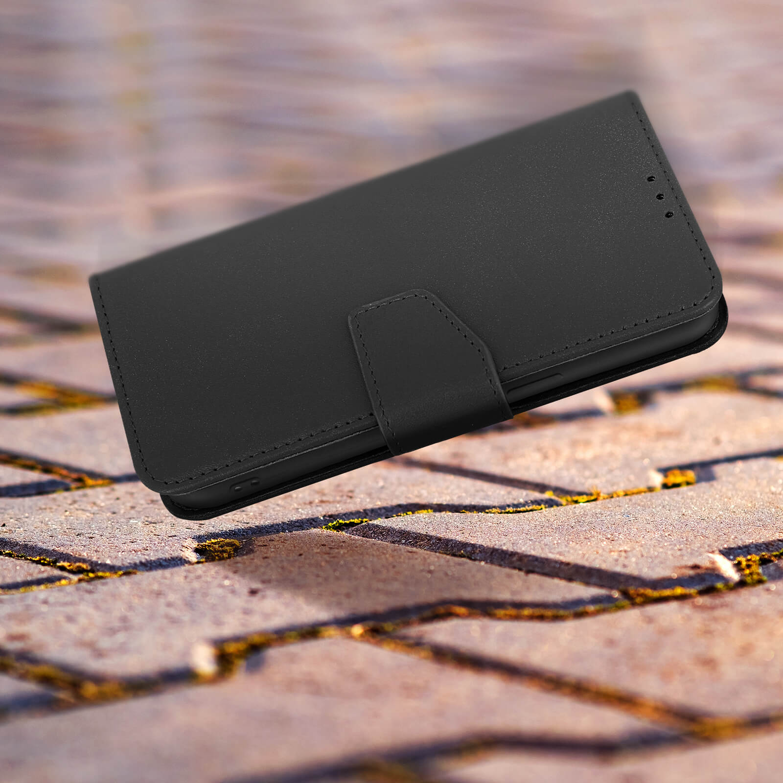 Un étui de téléphone noir est sur une surface en pierre. L'étui est fermé.