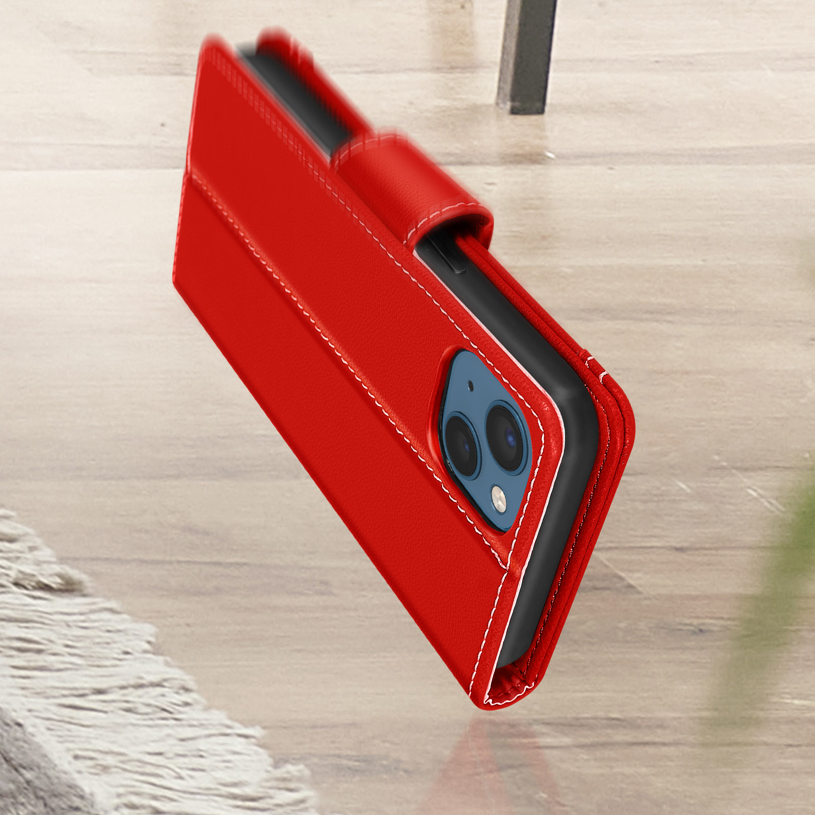 Coque de téléphone rouge avec coutures blanches, ouverte, sur une surface en bois.