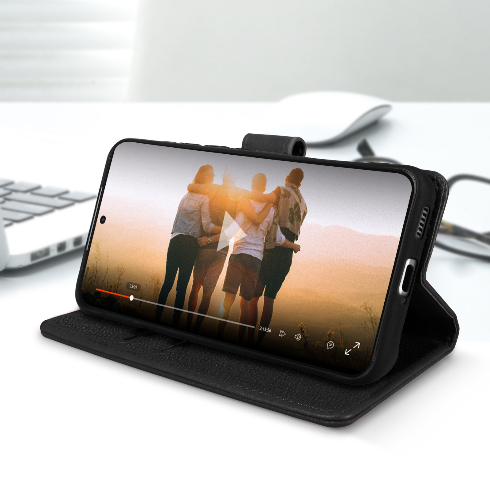 Coque de téléphone noire avec un téléphone affichant une vidéo de personnes. La coque est ouverte sur une surface blanche.