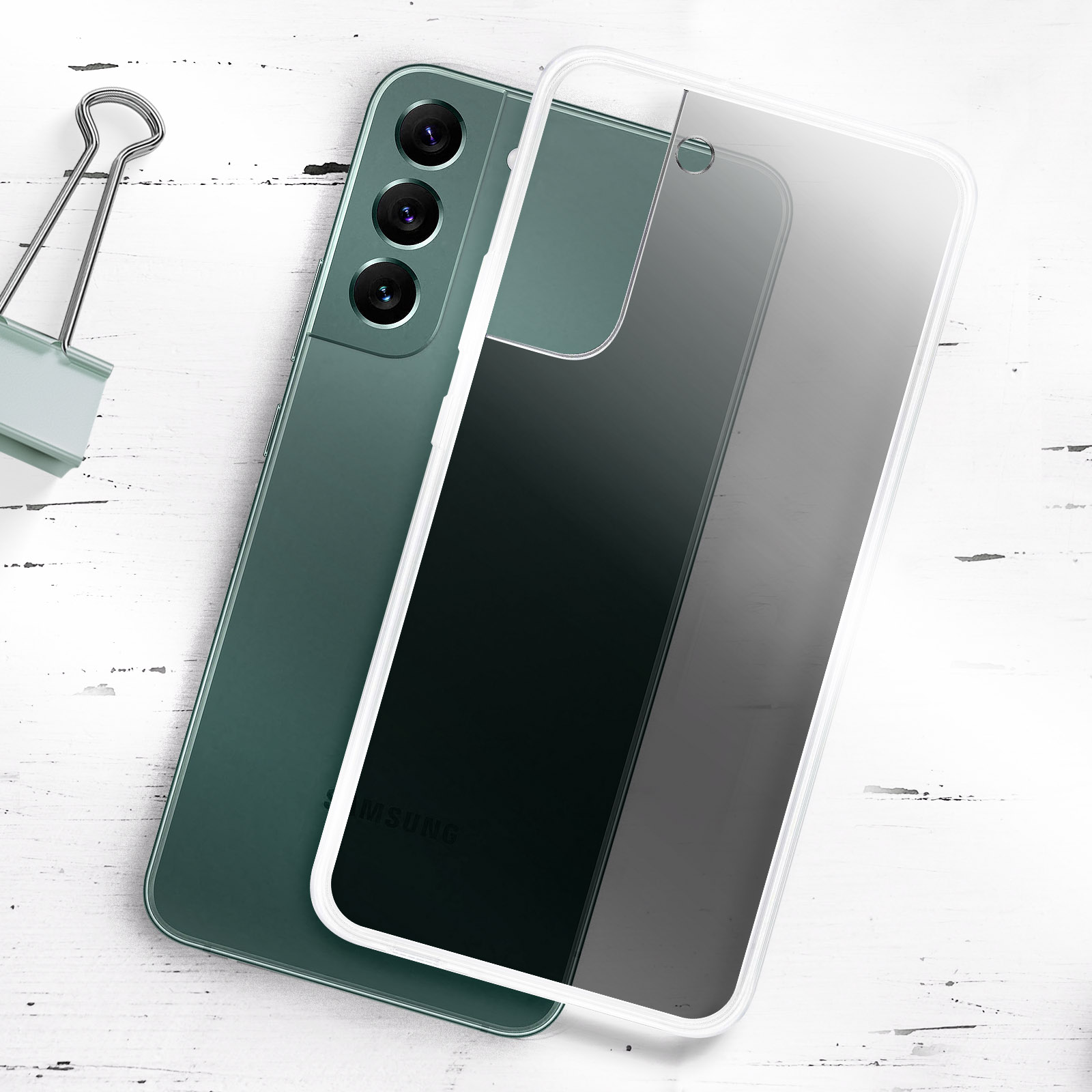 Teléfono verde con funda transparente puesta, sobre superficie blanca con clip.