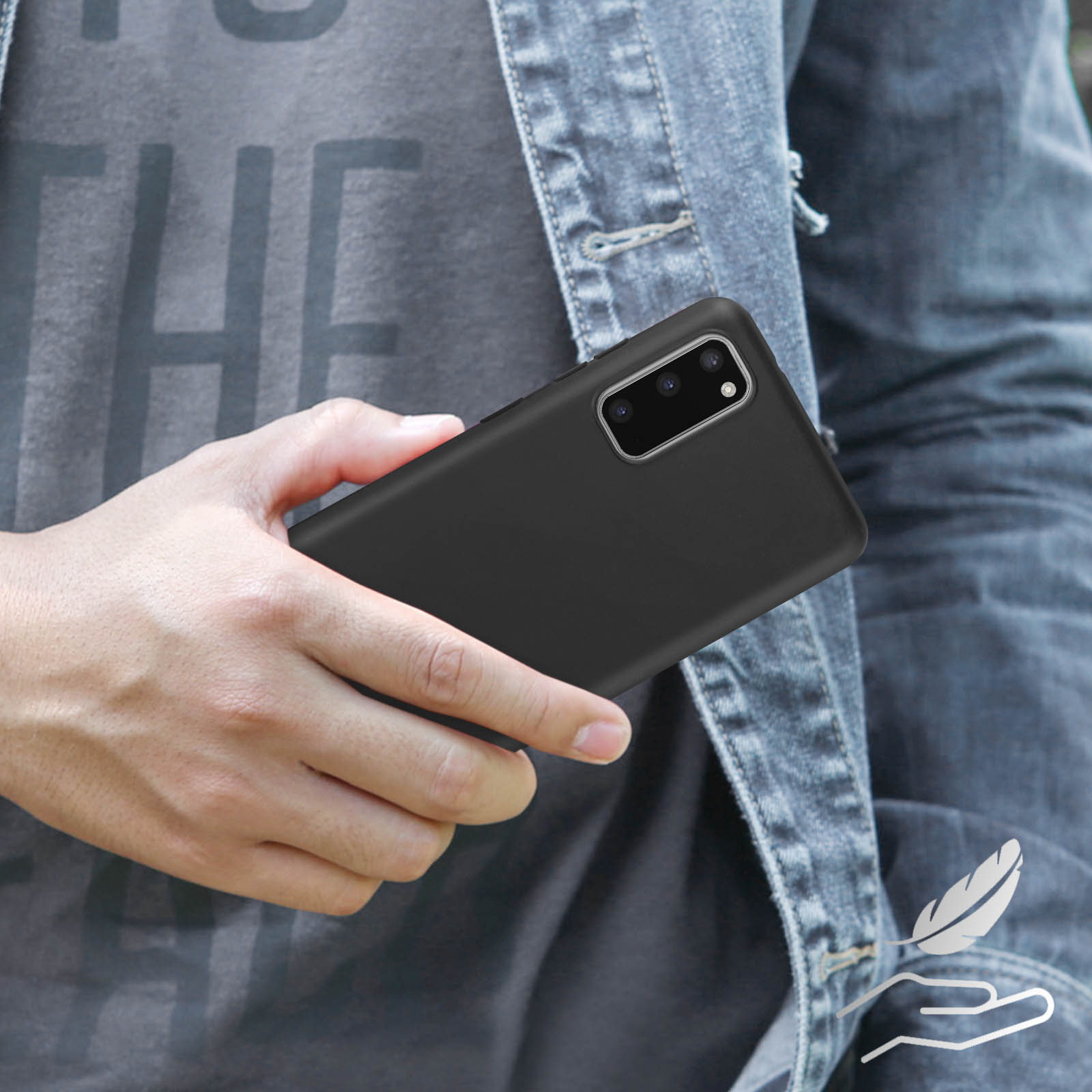 Mano che tiene un telefono nero, giacca di jeans sullo sfondo.