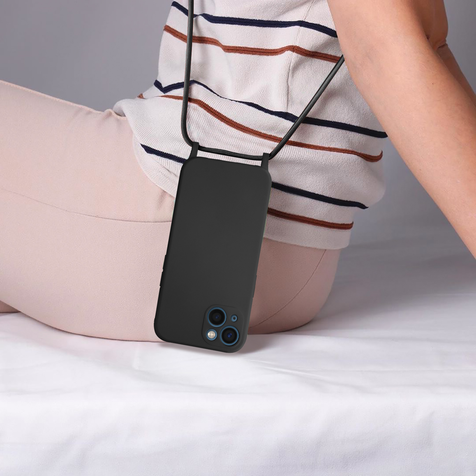 Persona con una camicia a righe, tiene in mano un telefono nero con un cinturino.