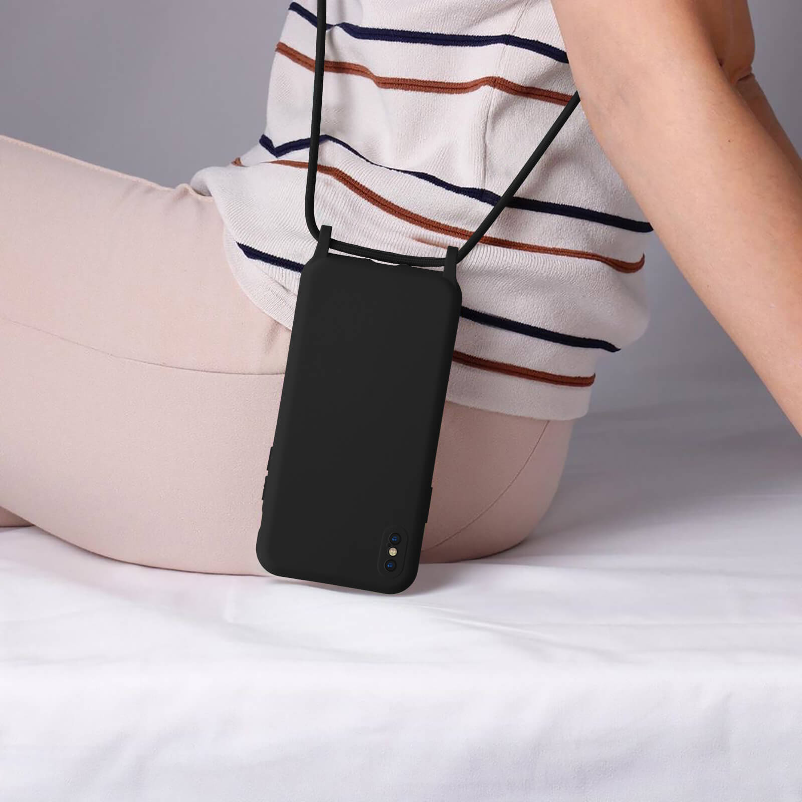 Coque de téléphone noire avec lanière, portée par une personne.