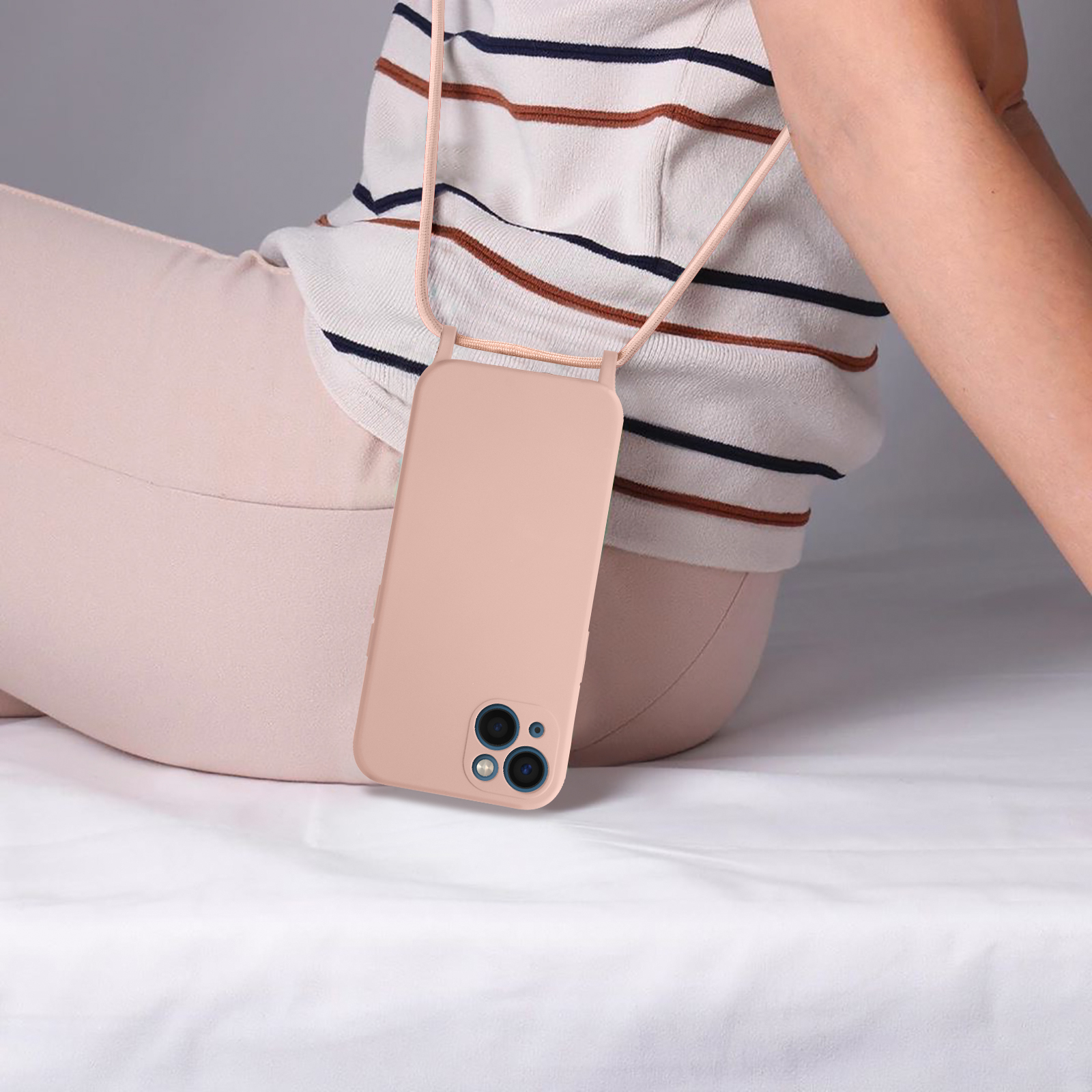 Un téléphone avec une coque rose est accroché à la poitrine d'une personne. La personne porte des vêtements clairs.