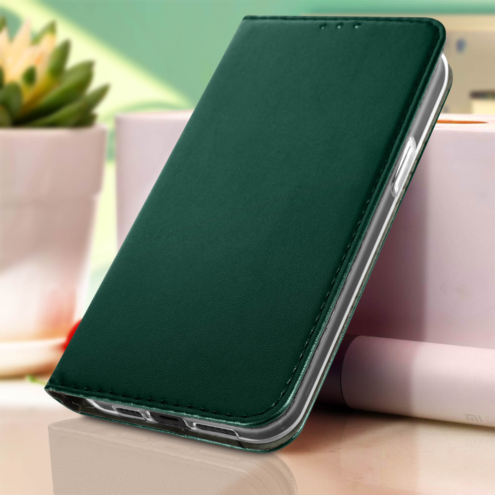 Una custodia per telefono verde. Sullo sfondo una scatola bianca e alcune piante.
