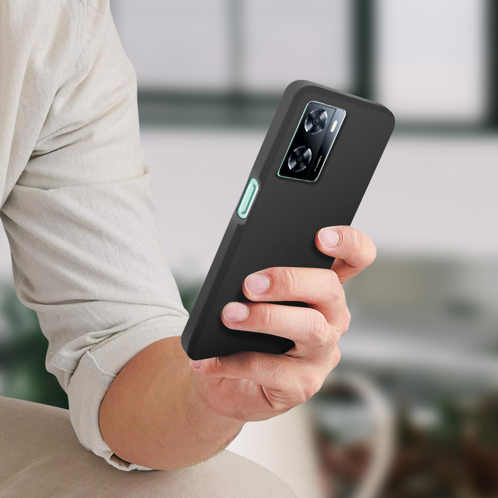 Una persona che tiene in mano un telefono nero. Lo sfondo è sfocato.