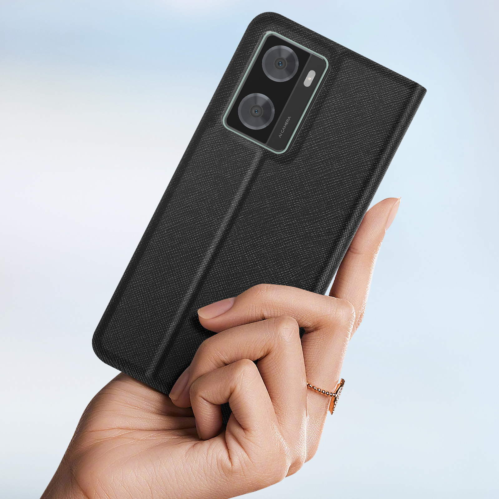 Hand hält eine schwarze Handyhülle. Telefon hat zwei Kameras. Hintergrund ist unscharf.