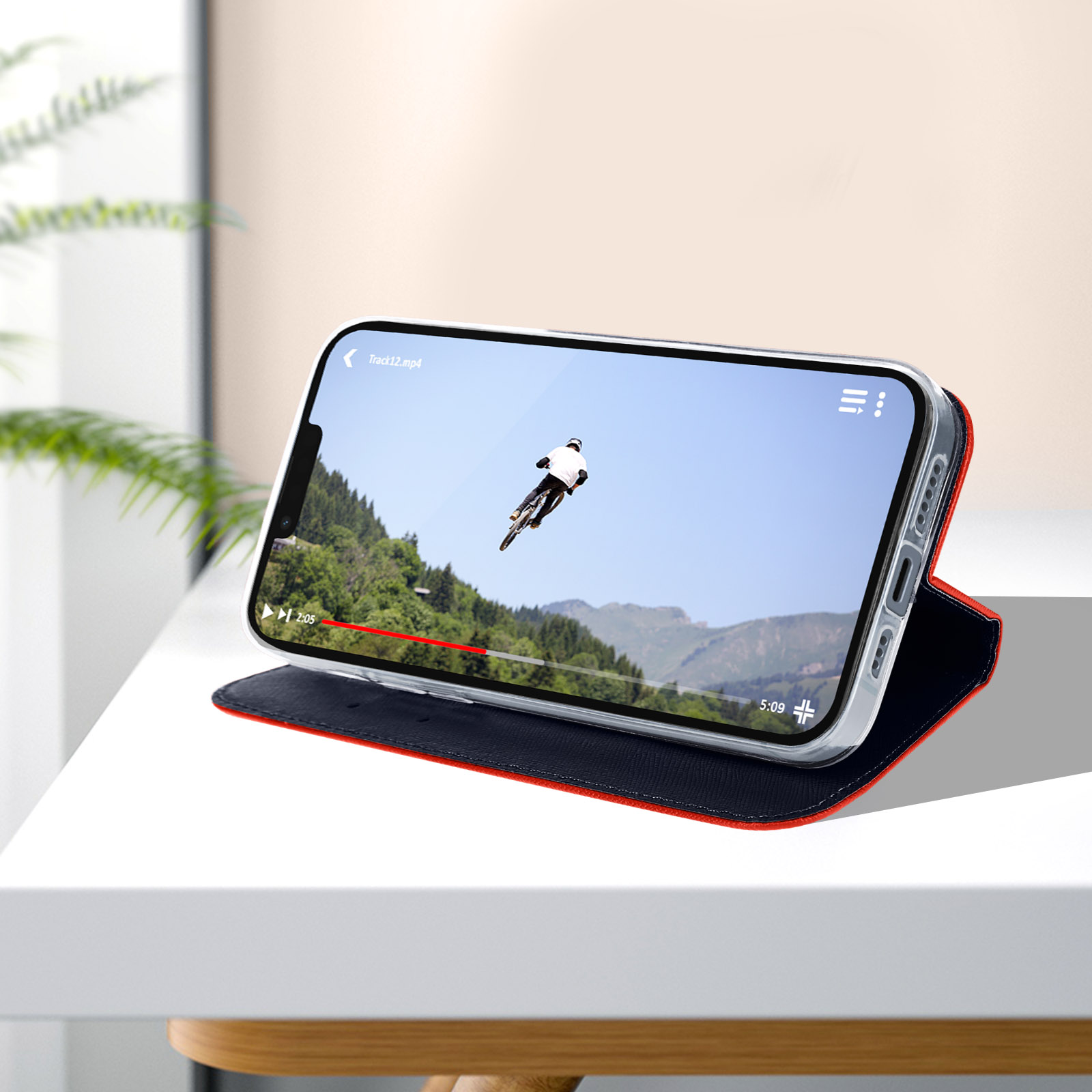 Telefono che mostra un video su un tavolo, con una custodia rossa e nera. La custodia è aperta.
