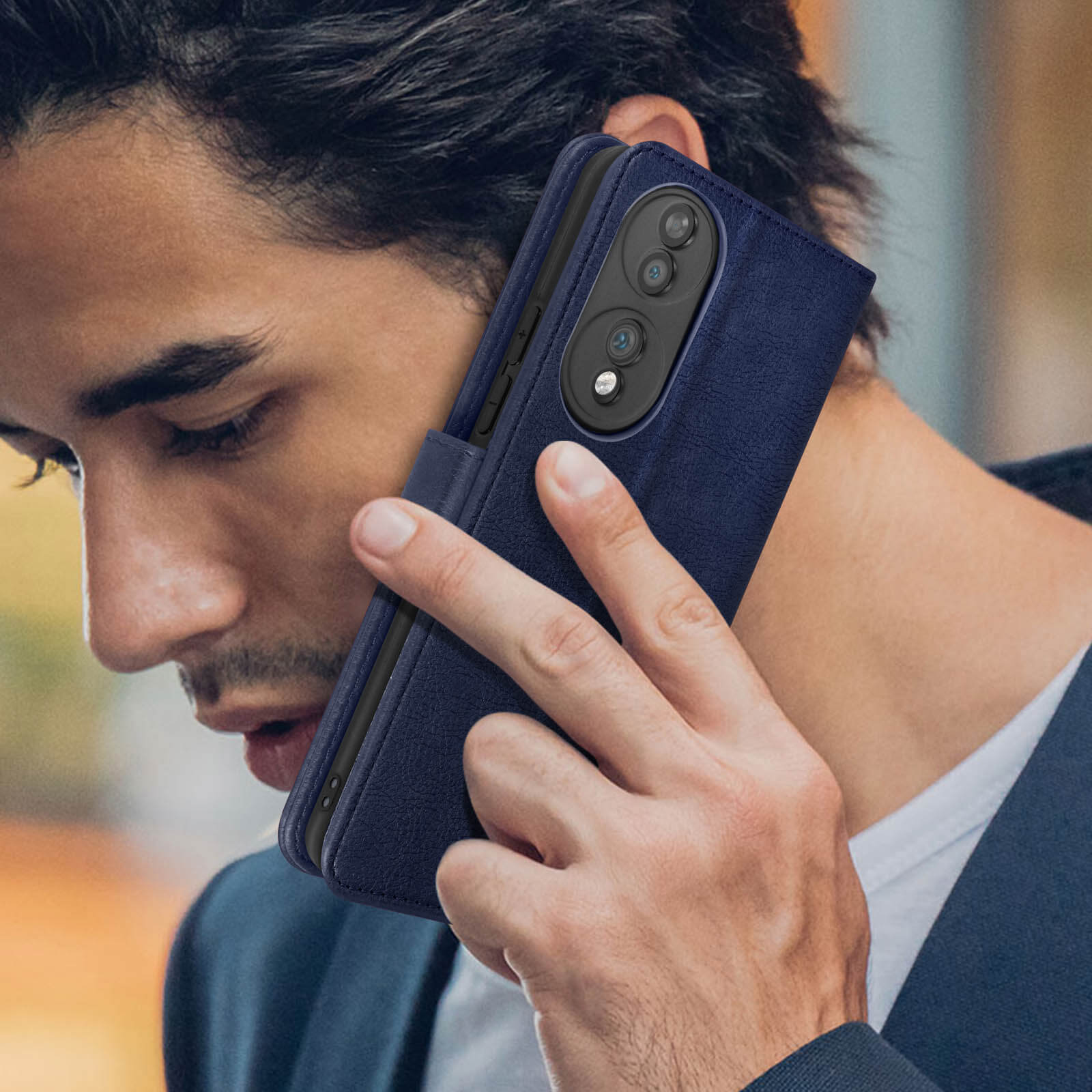 Uomo che tiene un telefono in una custodia a portafoglio blu. Il telefono ha un obiettivo della fotocamera.