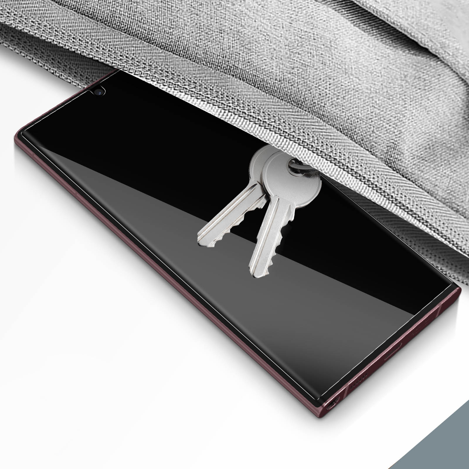 Uno smartphone con chiavi all'interno di una custodia grigia su una superficie bianca.