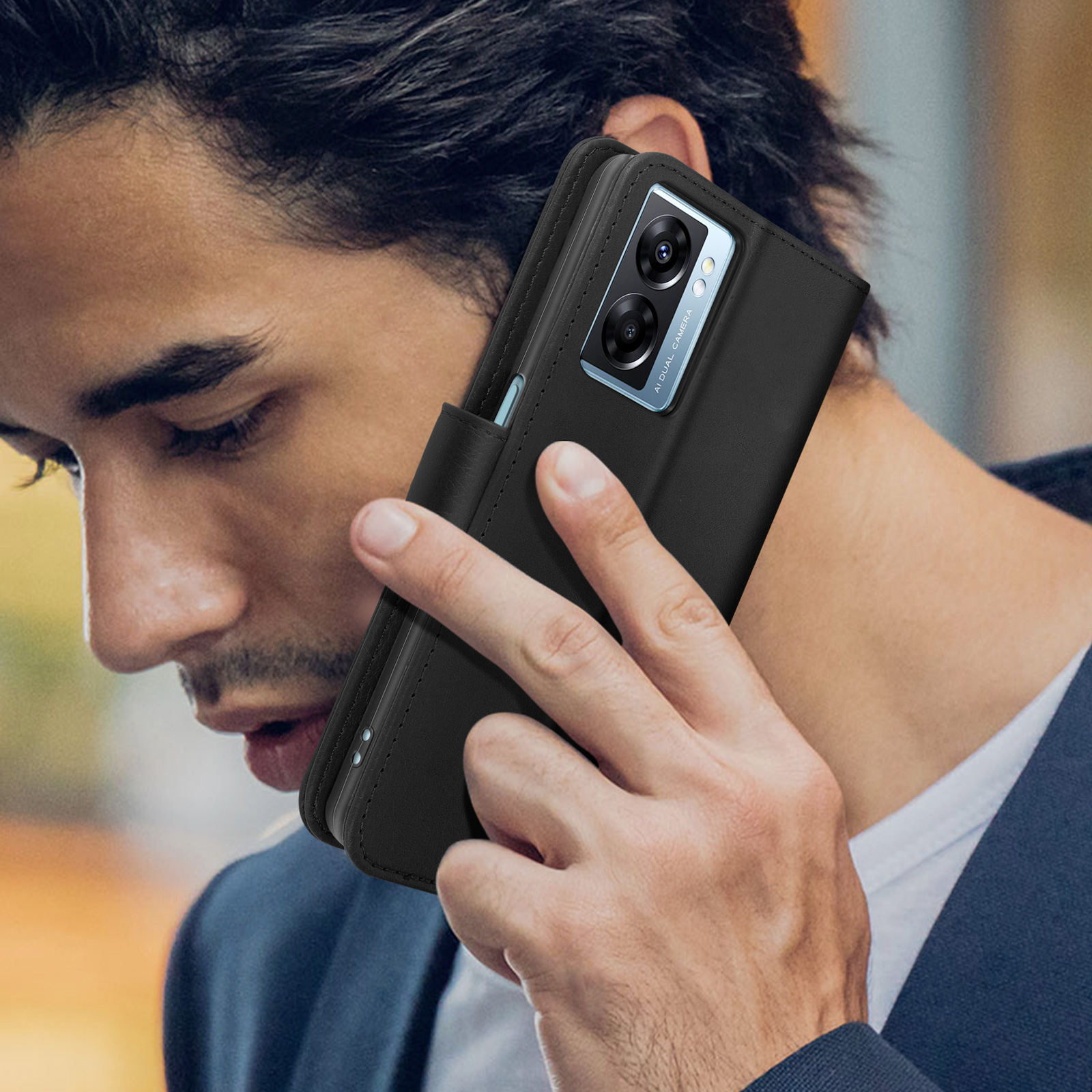 Uomo che tiene una custodia nera al suo orecchio. Il telefono è visibile.