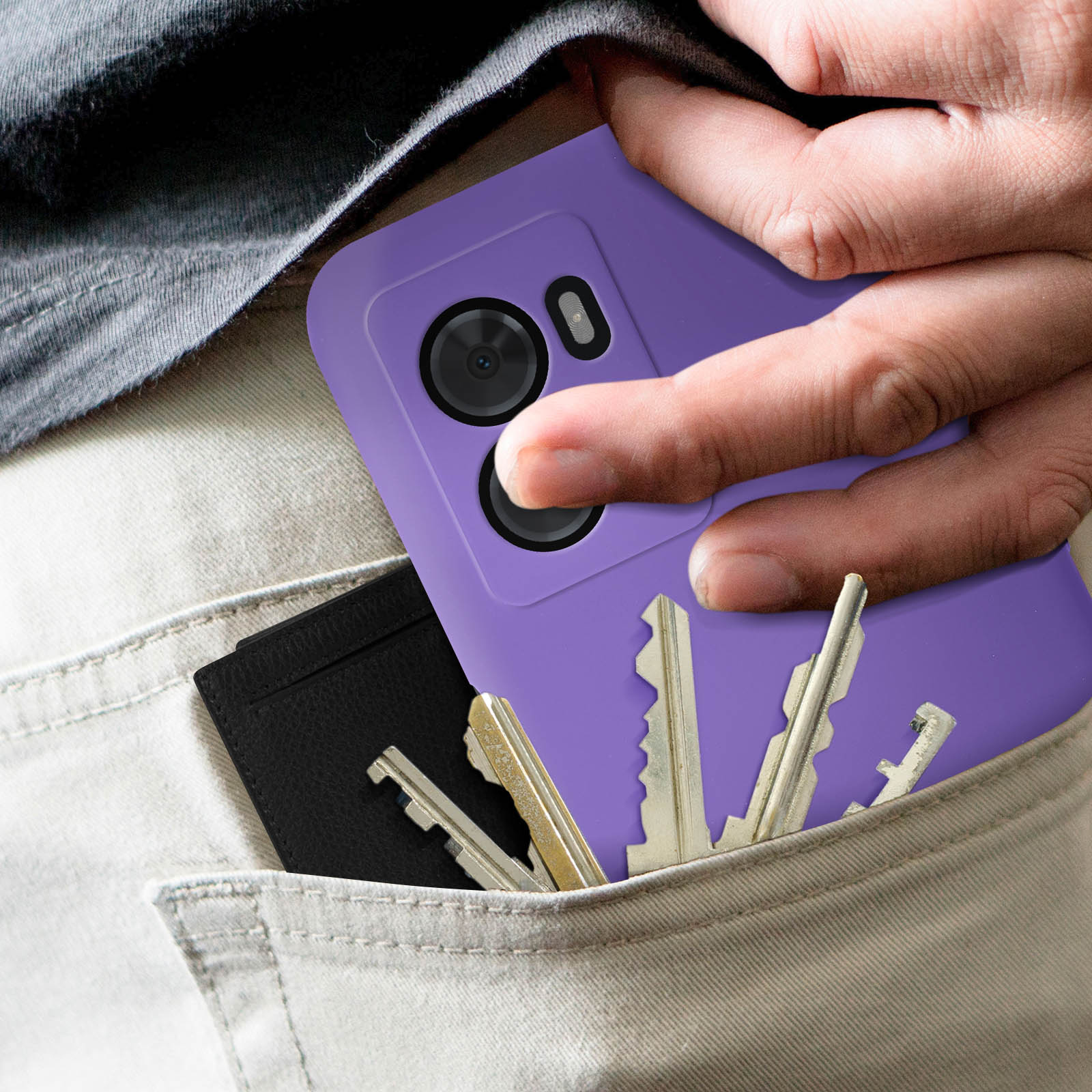 La mano di una persona in tasca con chiavi e una custodia viola per telefono. Un portacarte nero è anche in tasca.