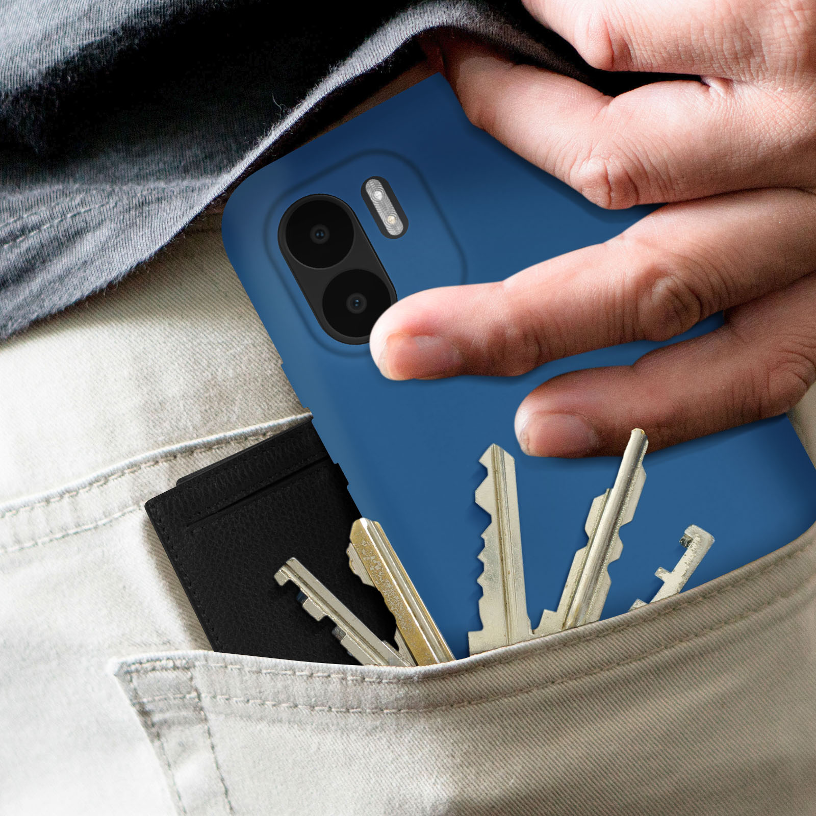 La main d'une personne tient un téléphone bleu avec des clés et un portefeuille dans sa poche.