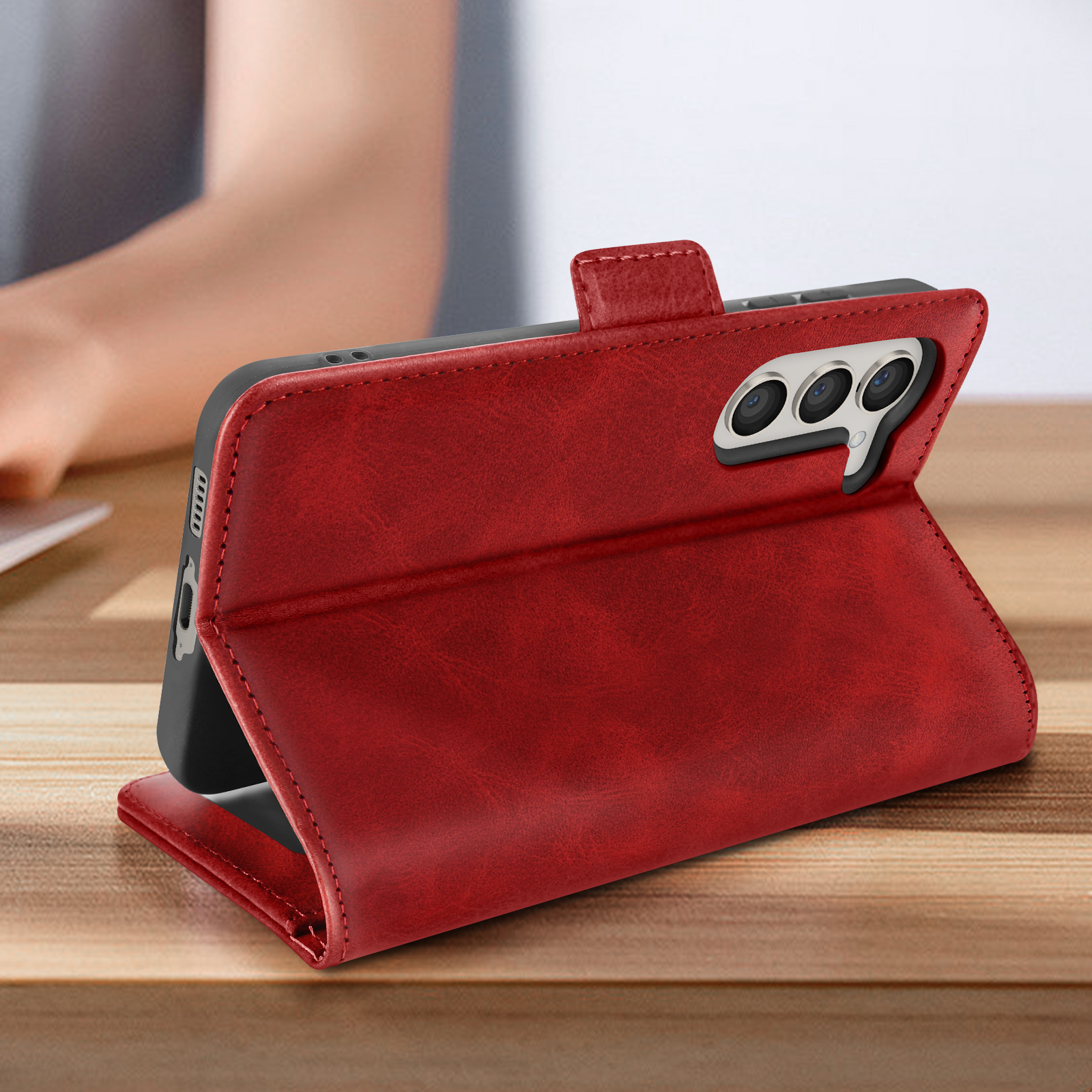 Custodia per telefono in pelle rossa aperta su una superficie di legno, che mostra il telefono e la fotocamera.